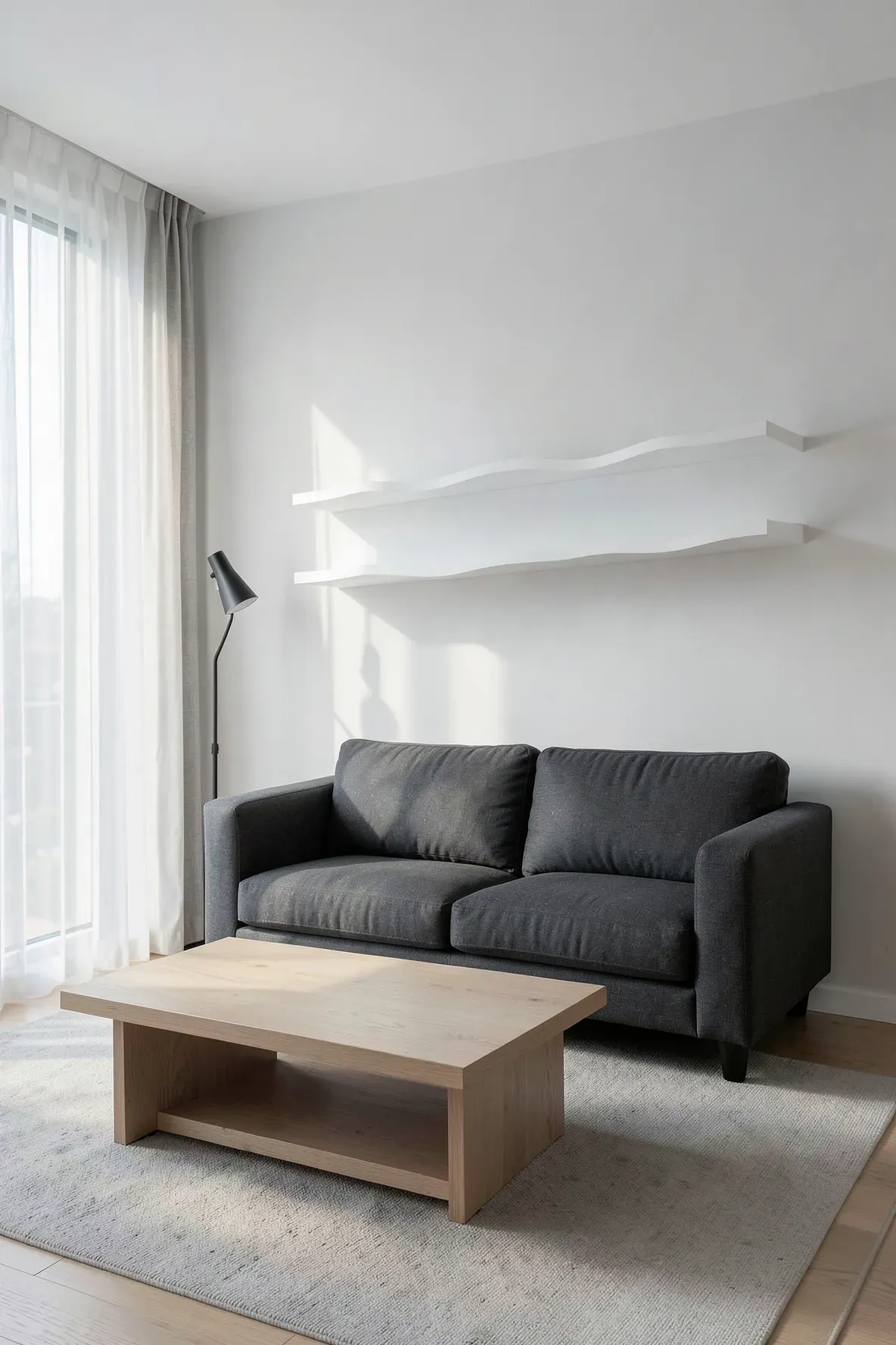 A modern living room with a boxy grey sofa and a long white wavy shelf mounted above it.