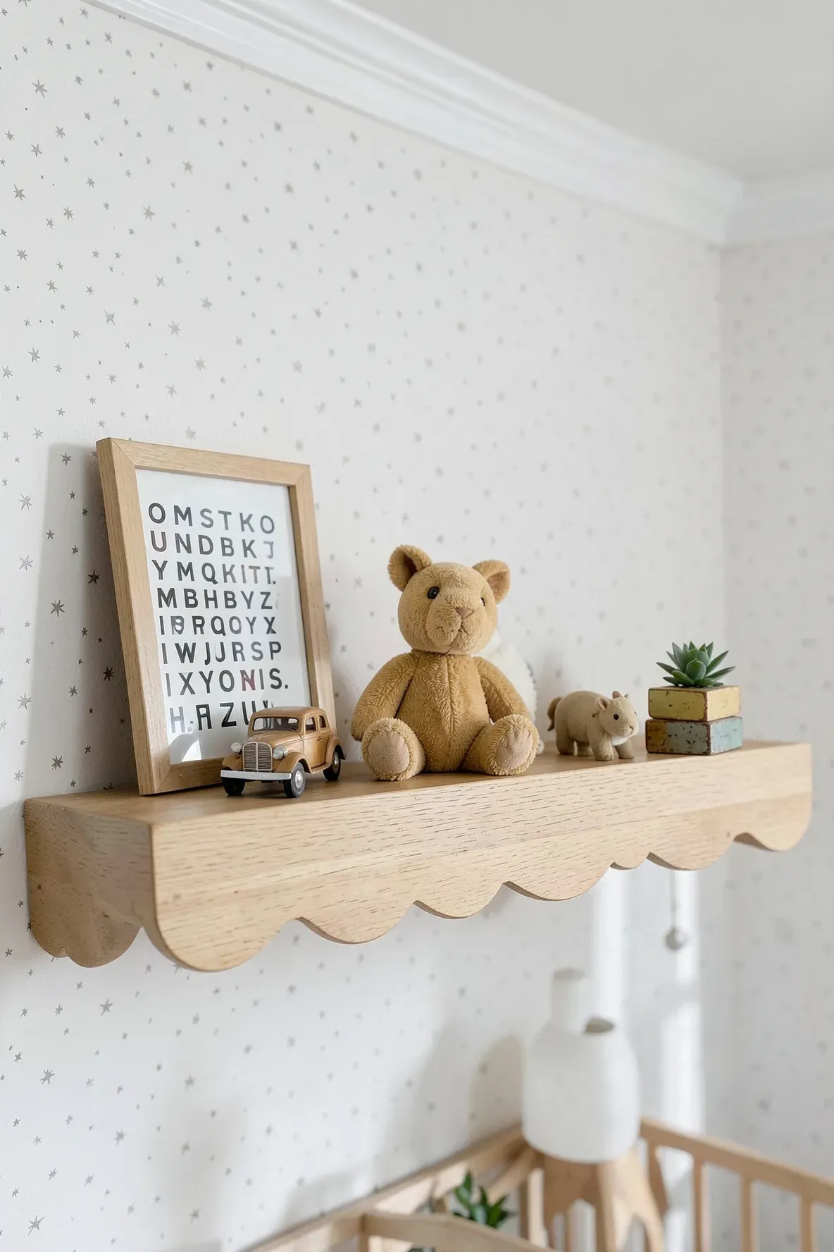 A styled oak scalloped shelf with a framed print, plush bunny, and wooden blocks.