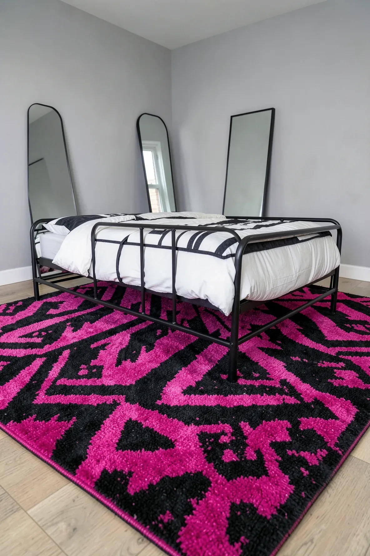 A bold black and hot pink geometric rug on the floor of a modern bedroom.