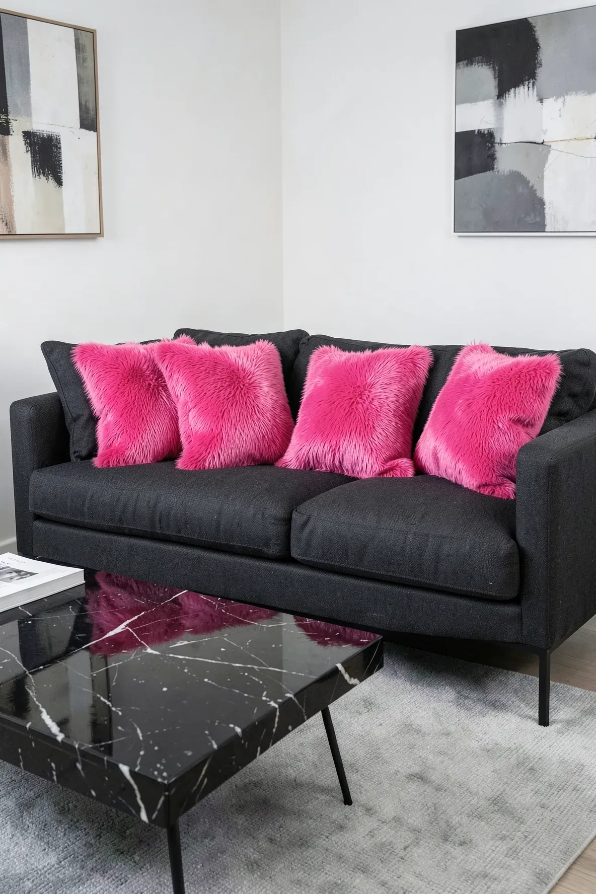 Bright hot pink throw pillows add a pop of color to a modern charcoal grey sofa.