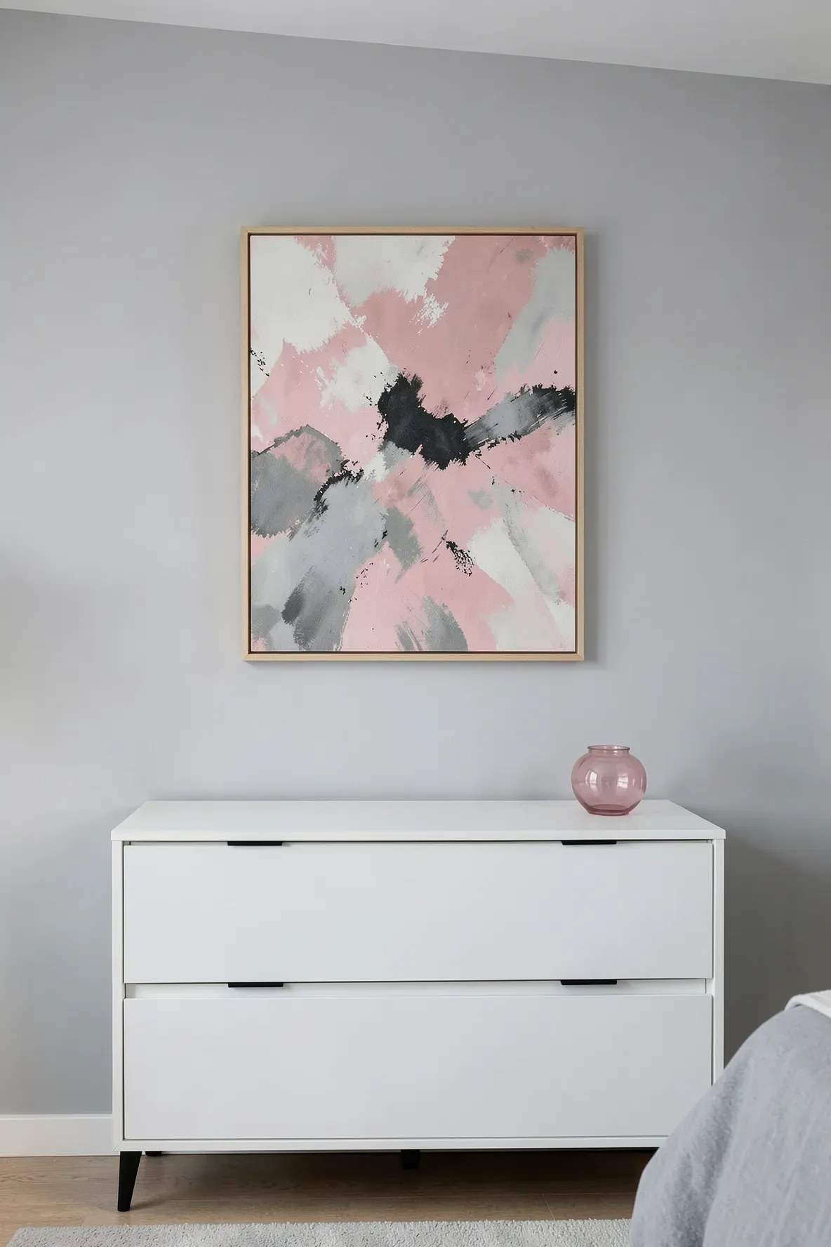 Muted pink and grey abstract art hanging above a white dresser in a calm bedroom.