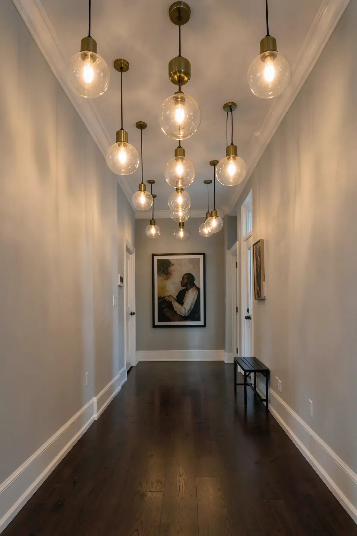 A row of four identical glass and brass pendant lights hanging in a long hallway.