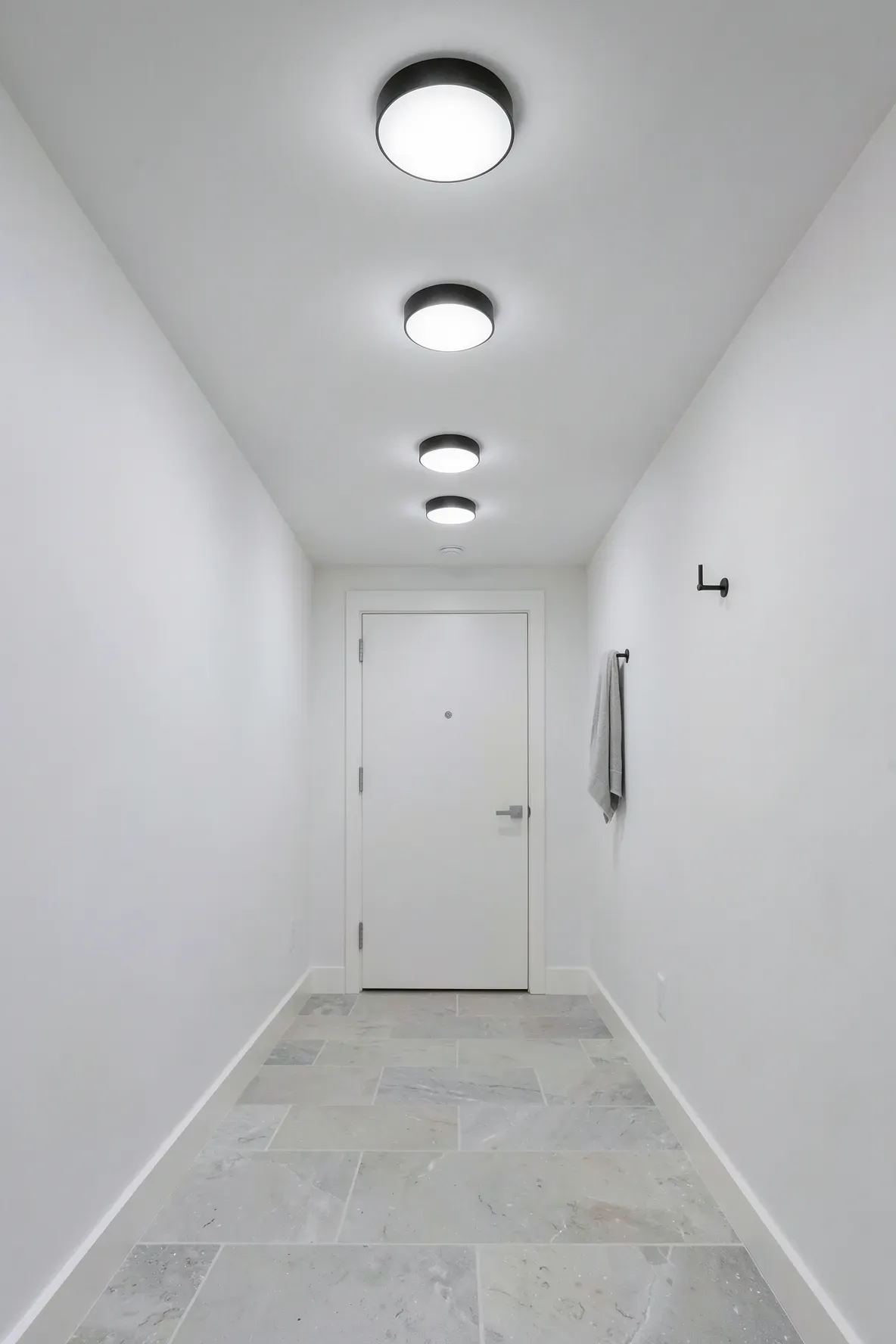 Modern slim black flush mount lights on a low hallway ceiling with white walls.