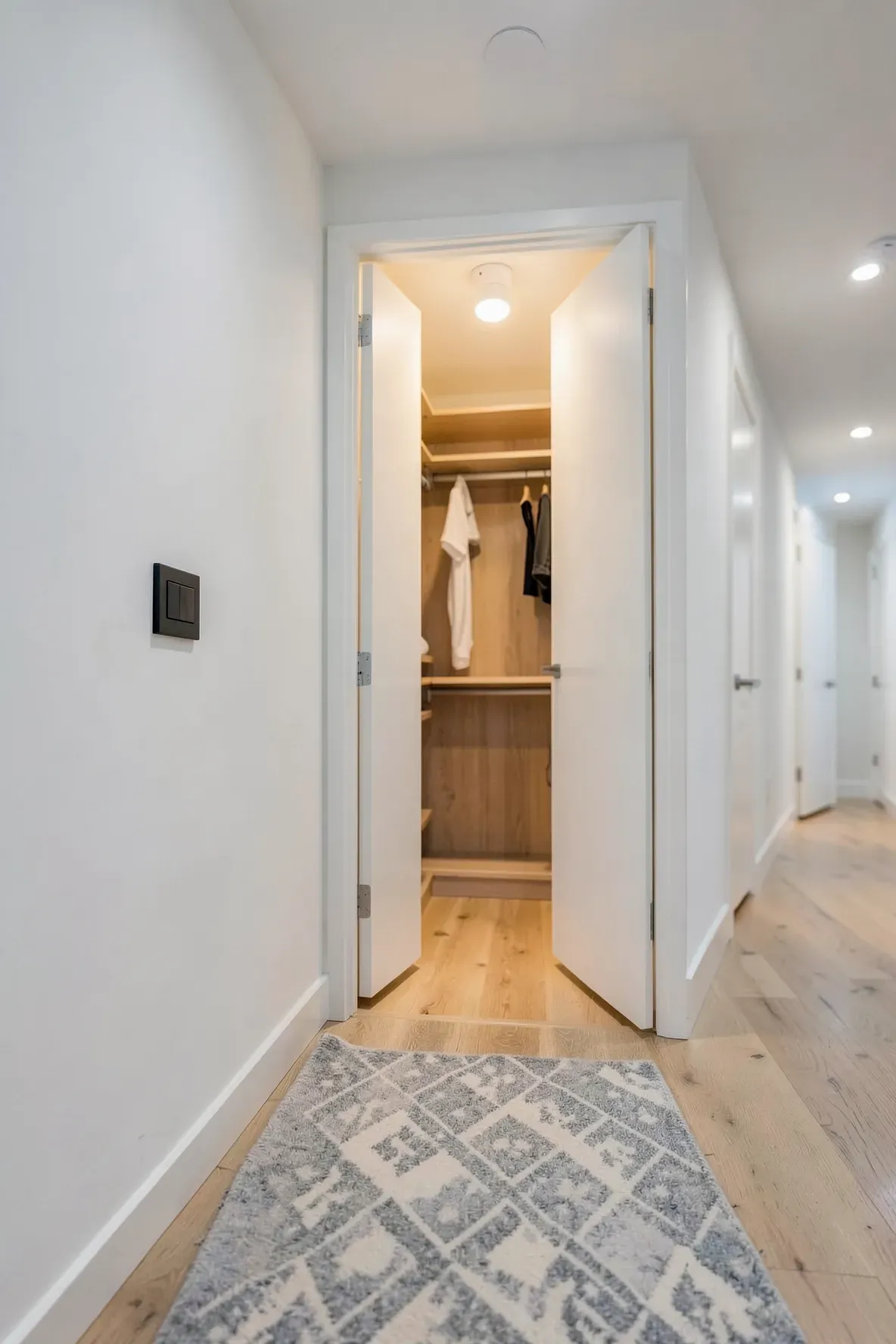 An open hallway closet illuminated by a bright LED motion sensor light showing organized shelves.
