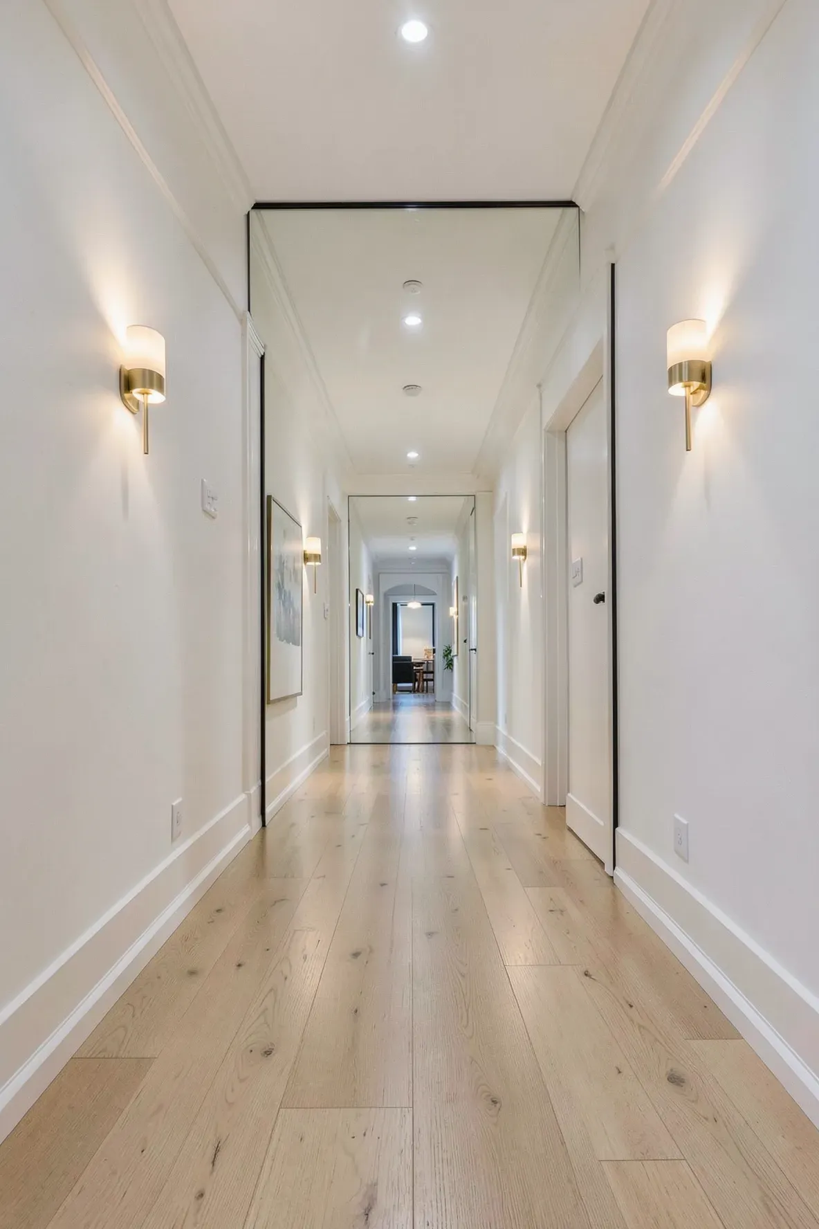 A long narrow hallway with a large mirror at the end creating an illusion of extra space.