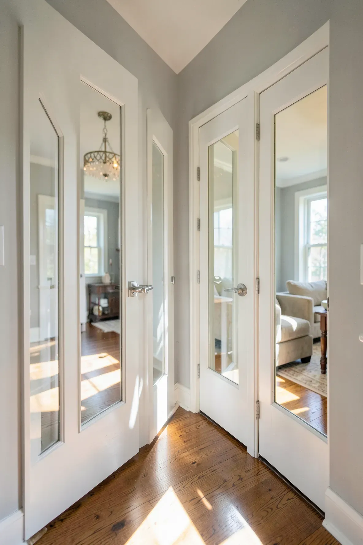 A hallway with white doors featuring glass panels that let light shine in from other rooms.