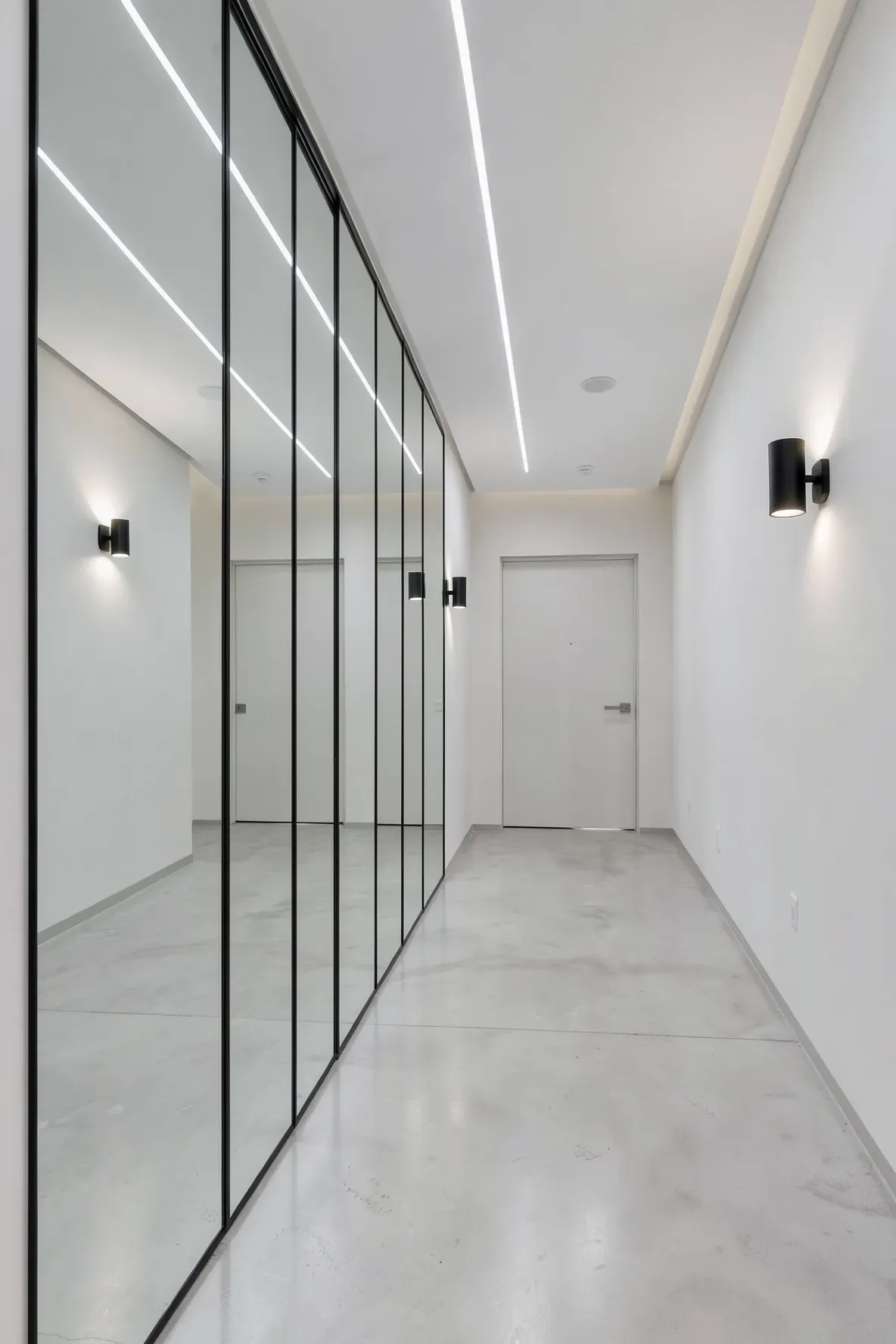Floor-to-ceiling mirror panels on a hallway wall creating a spacious reflection.