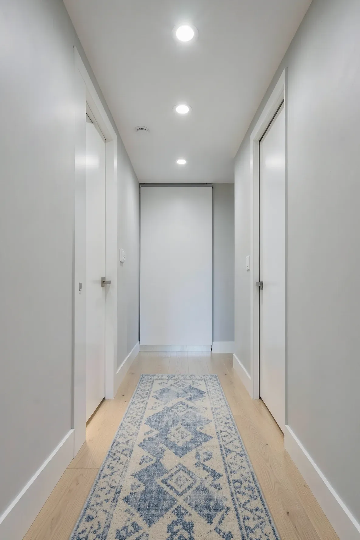 A narrow hallway with white pocket doors that slide into the walls to save space.