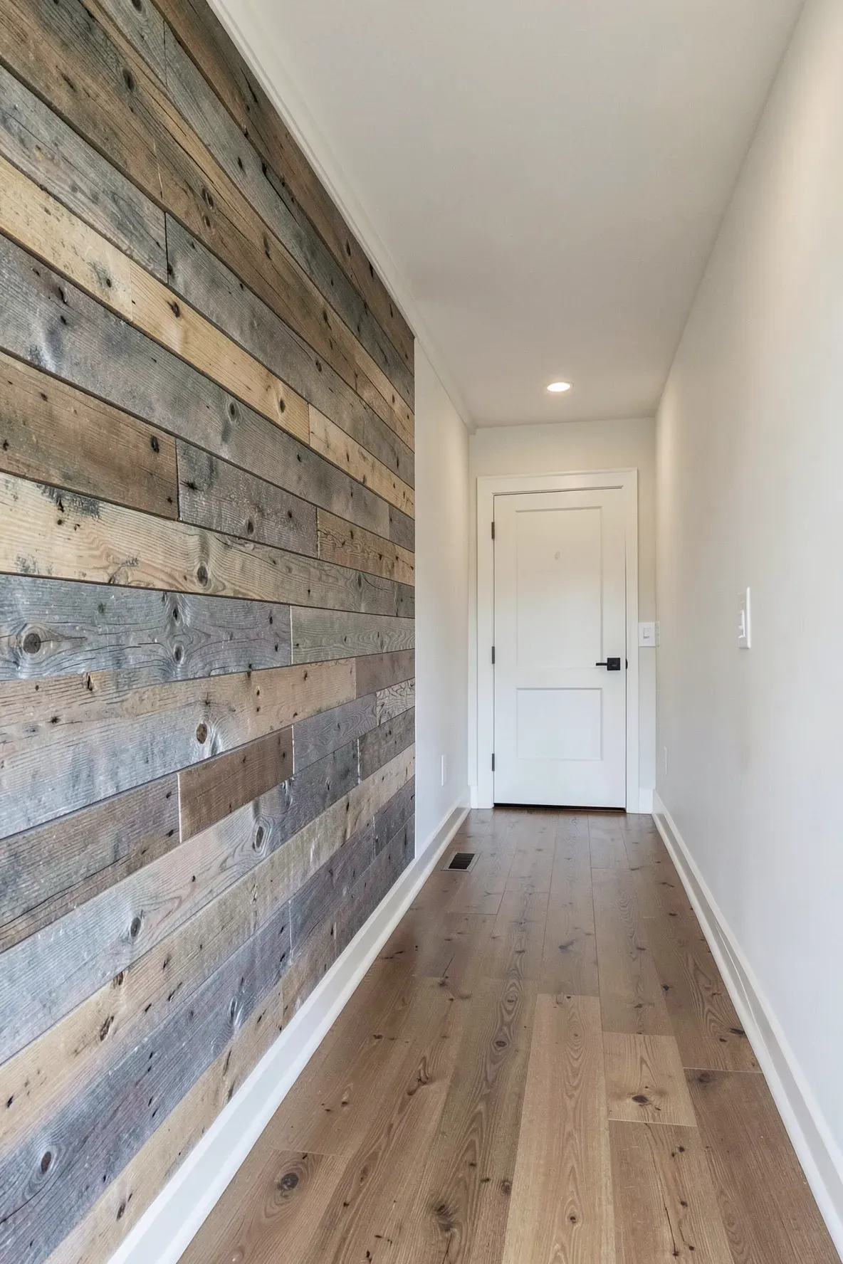 A long narrow hallway featuring a rustic reclaimed wood horizontal shiplap accent wall.