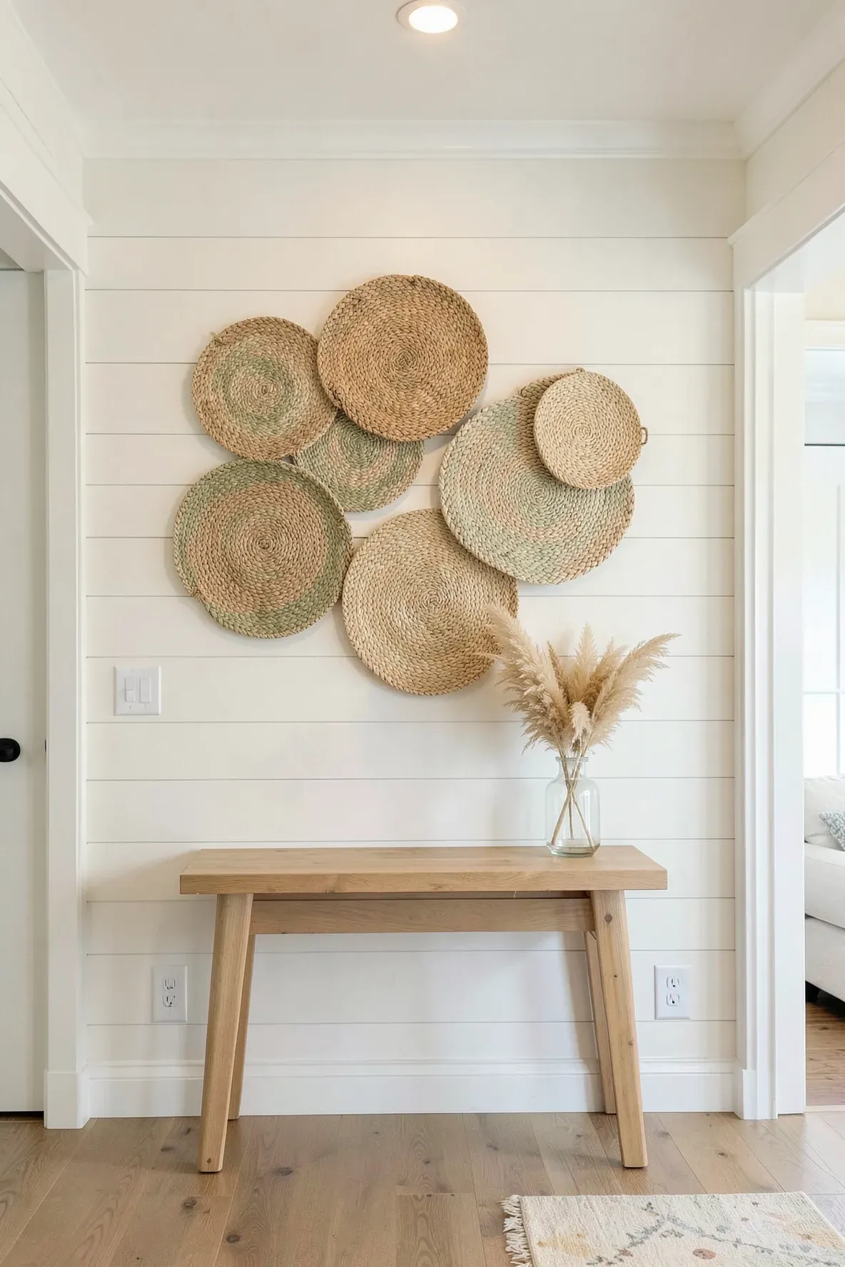 A cluster of woven seagrass baskets hanging on a white hallway wall.