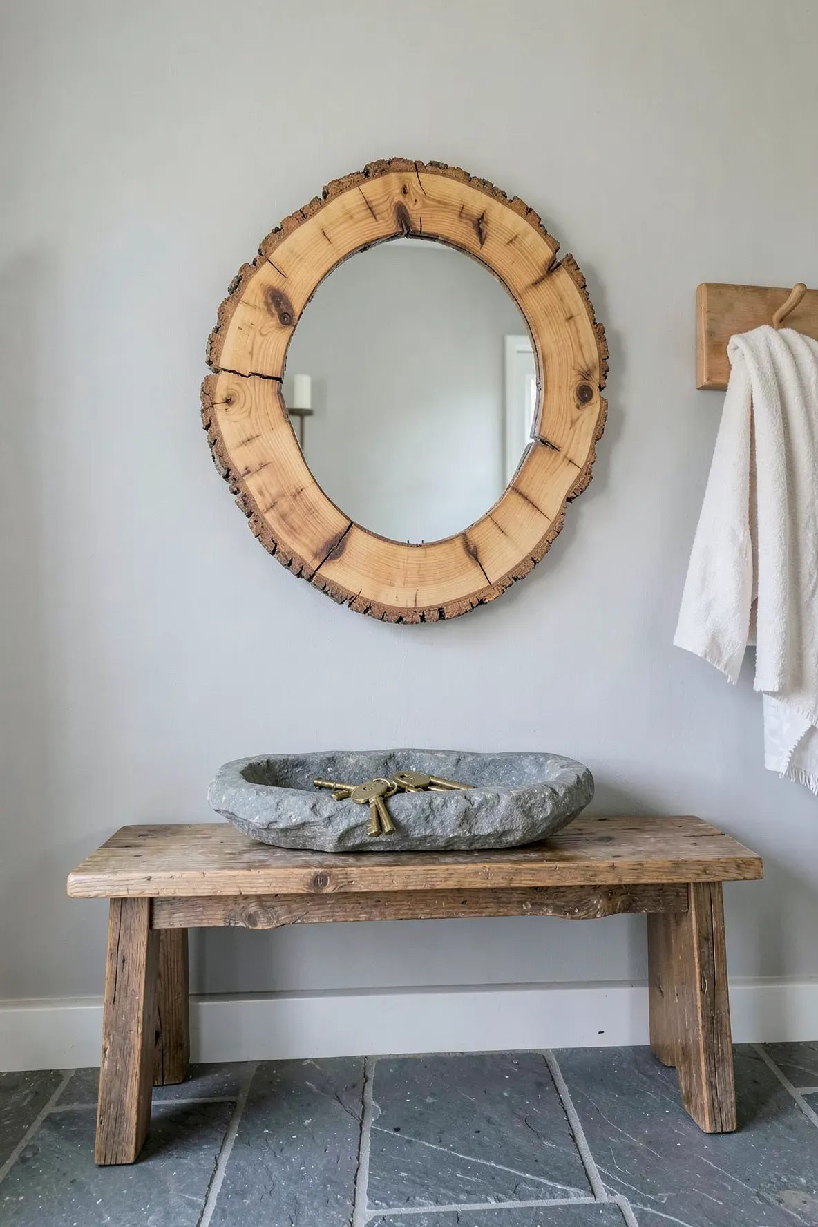 A round mirror with a rustic wood slice frame hangs in a farmhouse-style entryway.