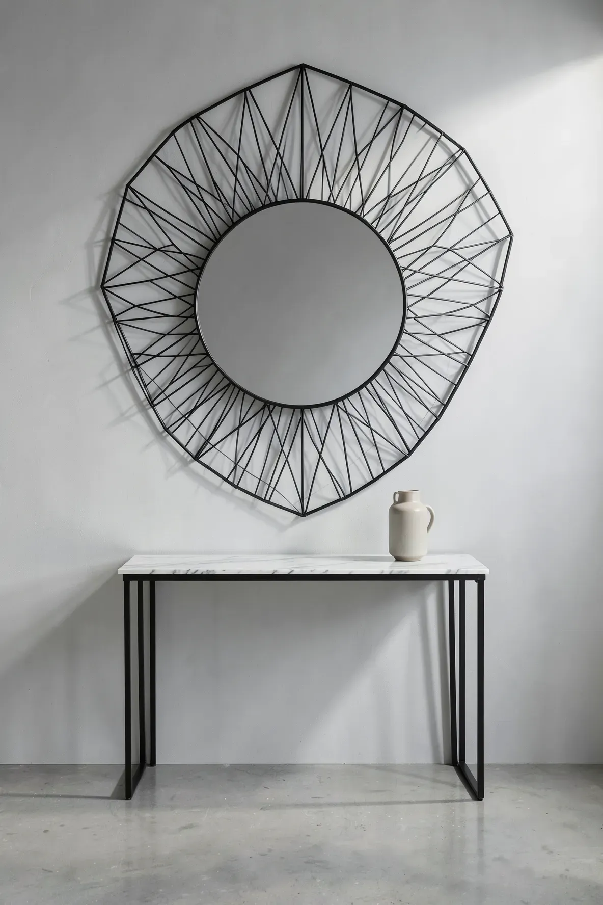 A modern round mirror with a black geometric wire frame on a minimalist grey wall.