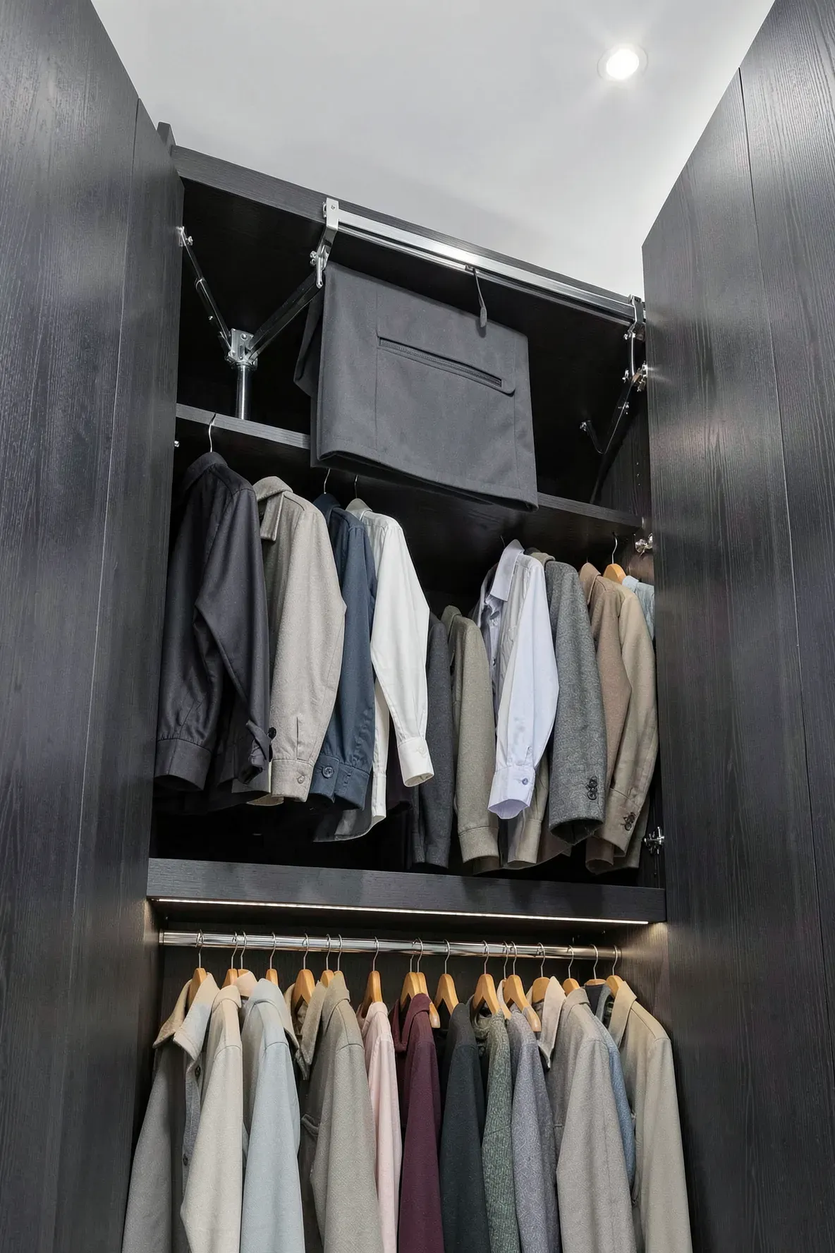 A high-ceilinged built-in closet with a chrome pull-down rail bringing clothes to a reachable level.
