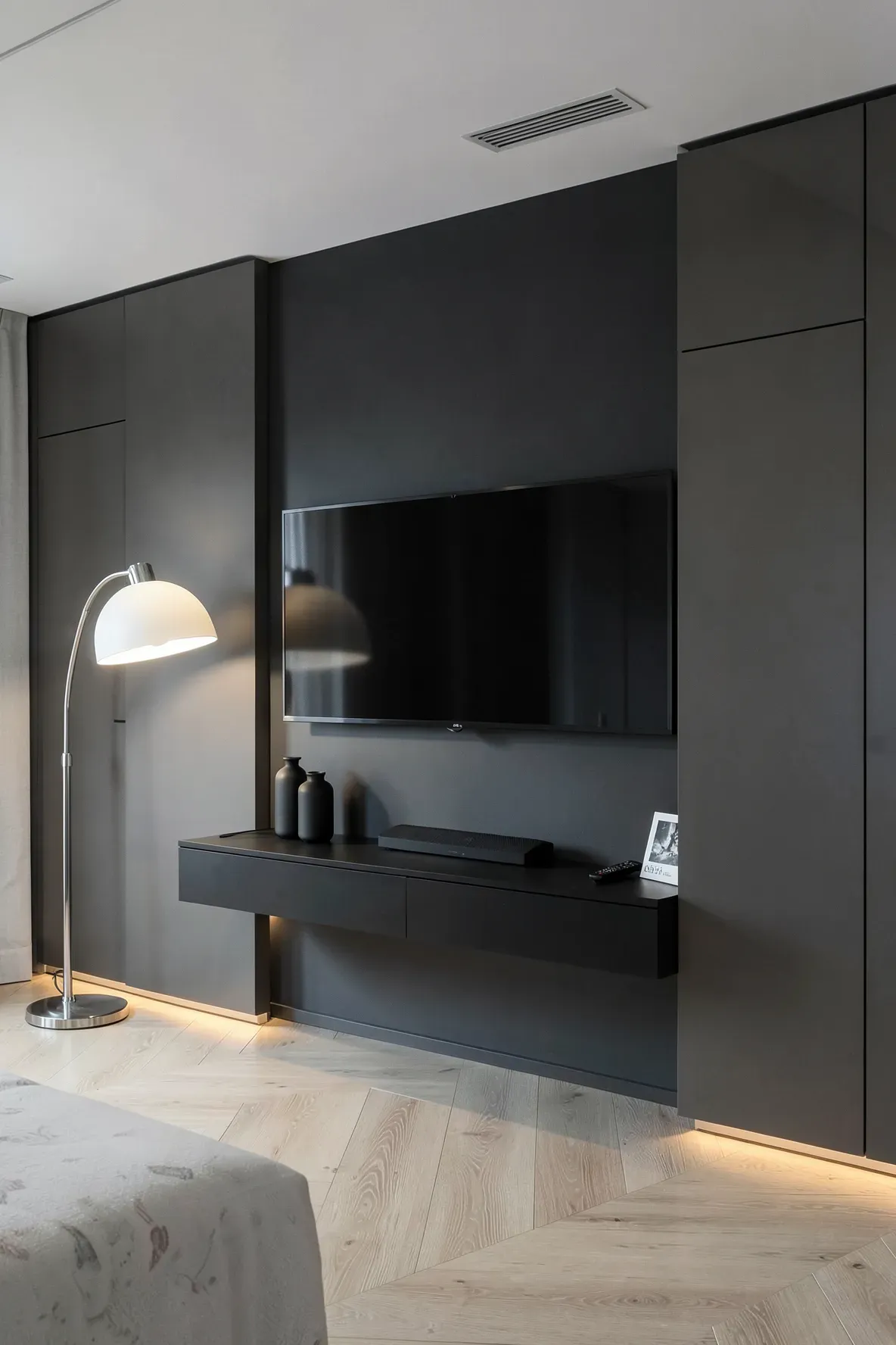 A minimalist black floating console between two white wardrobes with a wall-mounted TV above it.