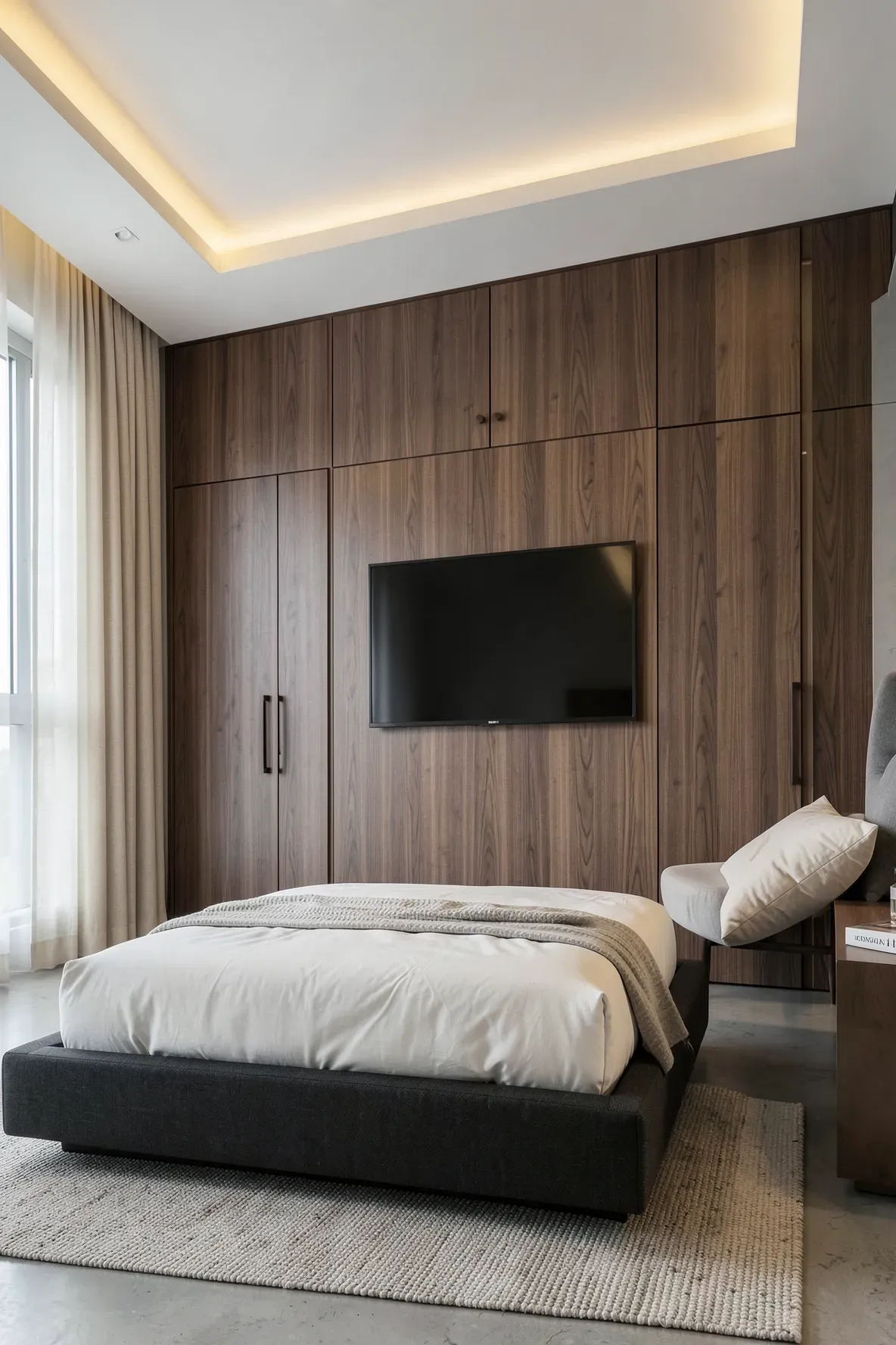 A luxury bedroom with a walnut wood-paneled wall hiding a closet and a flush-mounted TV.