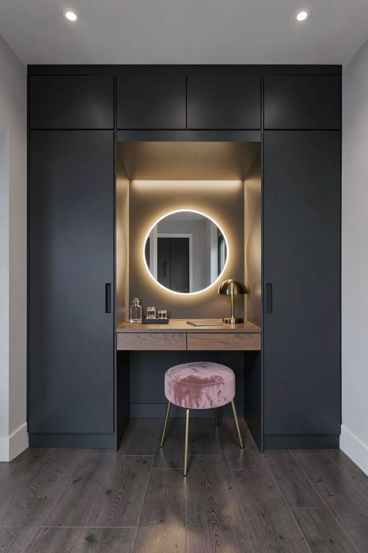 A dark charcoal full-wall closet with a central built-in vanity desk and a backlit mirror.