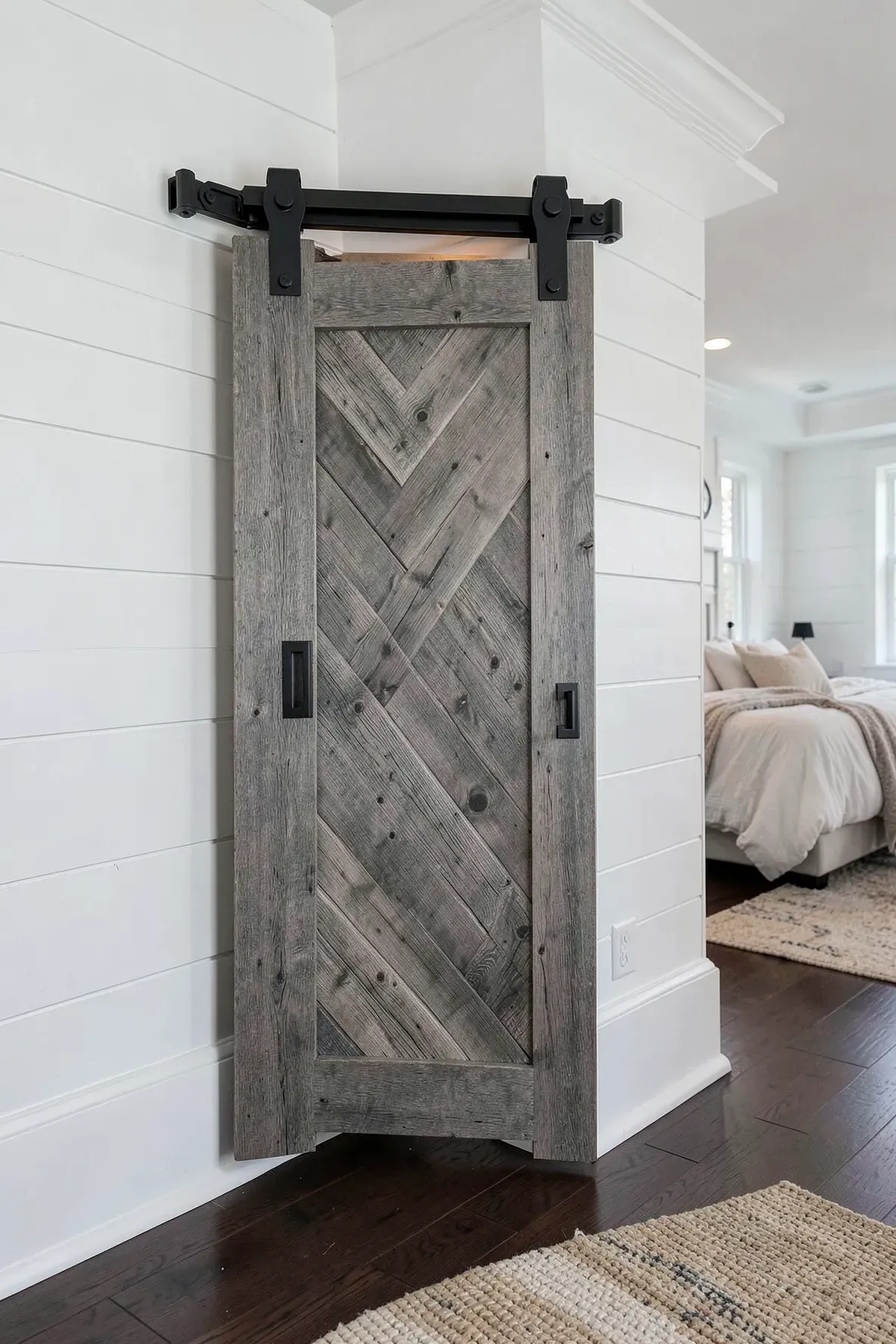 A rustic sliding barn door on a black track covering a corner closet in a bedroom.