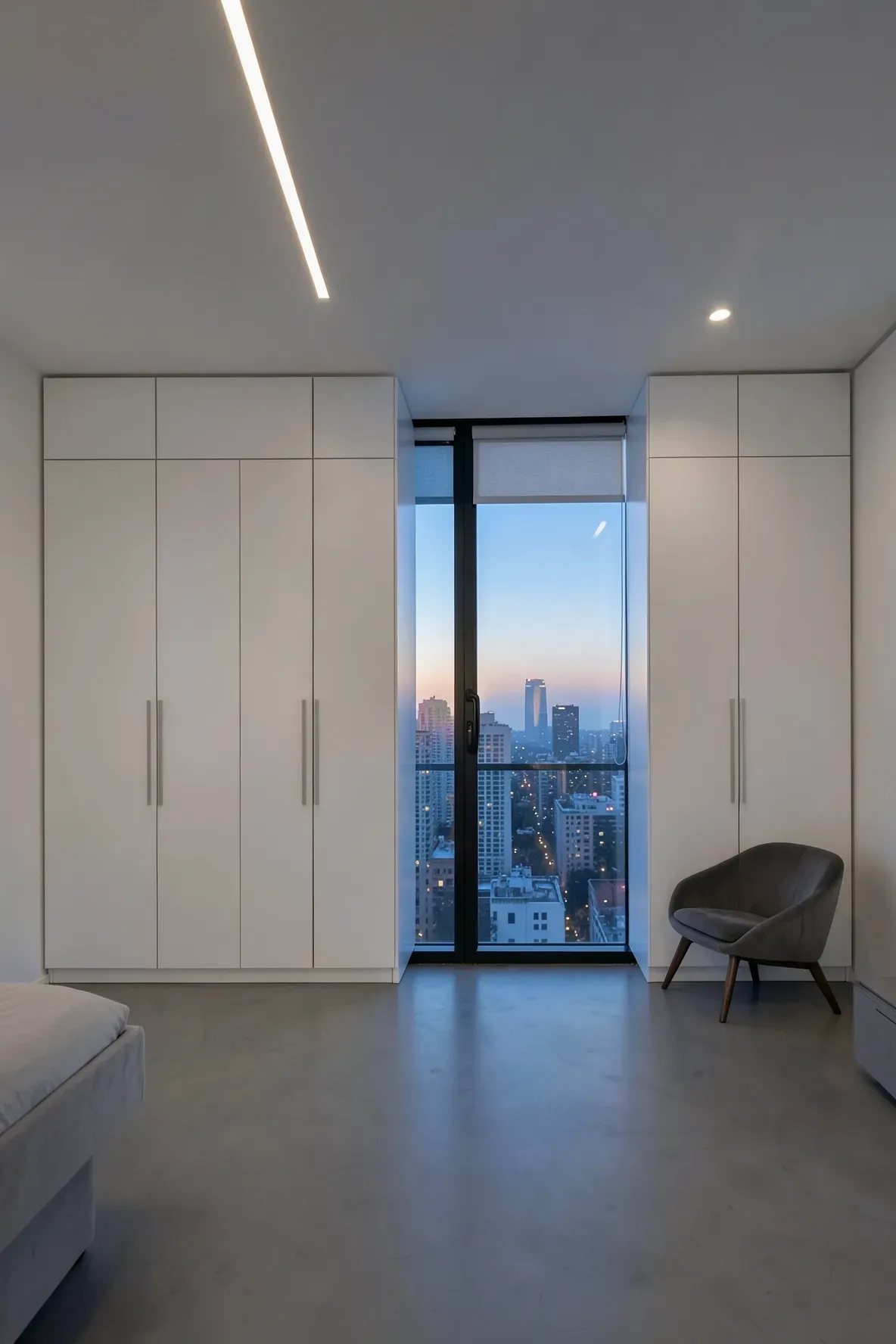 Sleek handleless white wardrobes creating a seamless wall around a modern bedroom window.