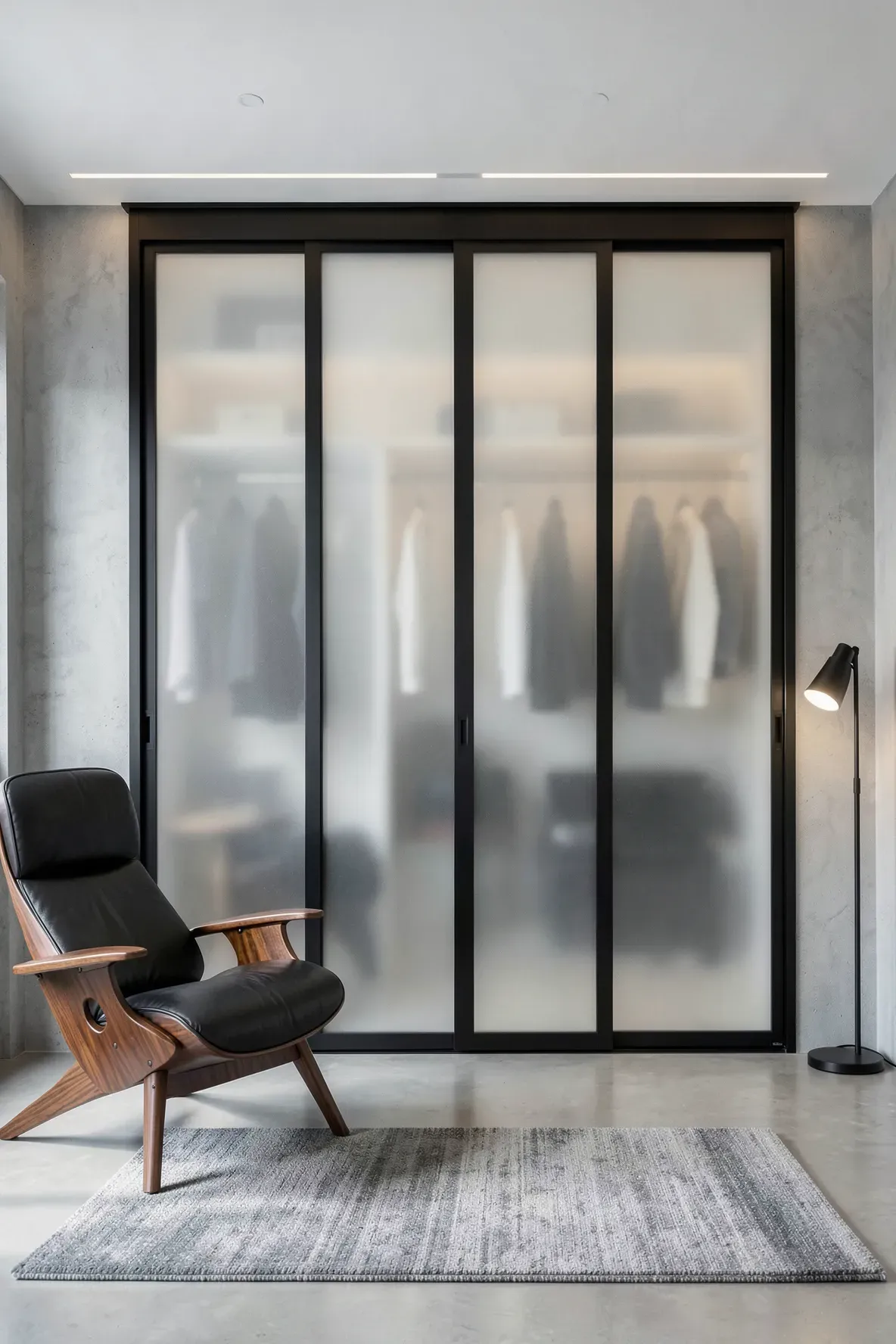 Modern frosted glass sliding wardrobe doors with slim black aluminum frames in a loft bedroom.