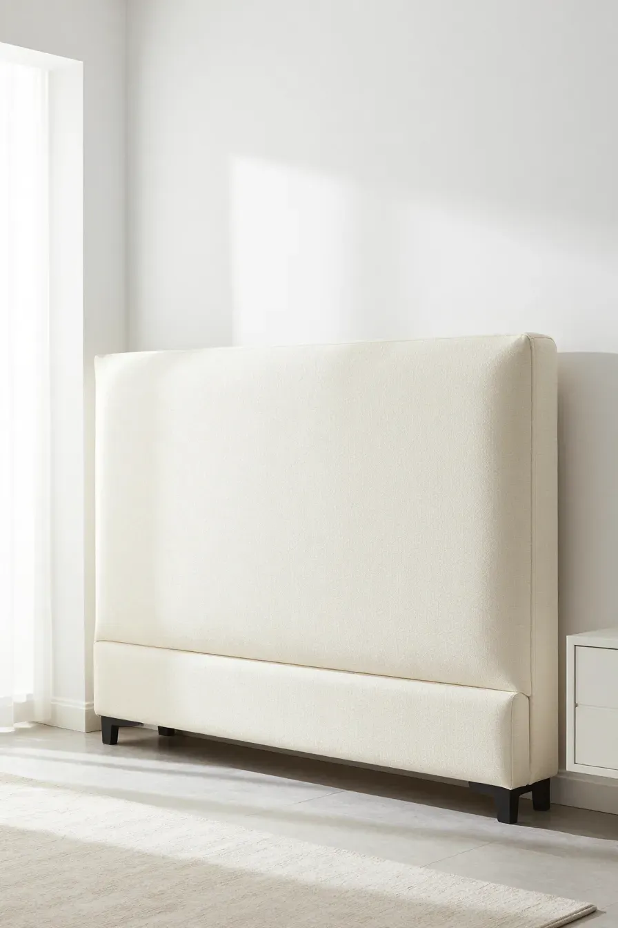 A bright and airy bedroom showing a pristine, clean cream upholstered headboard in a sunlit room.