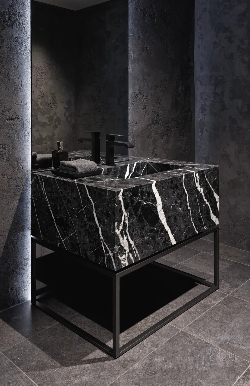 A sleek black marble vanity top on a thin black steel frame in a moody, modern bathroom.