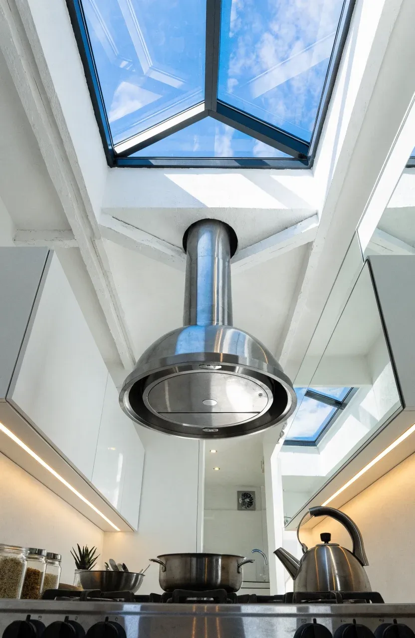 A tiny home kitchen with a skylight, stainless steel range hood, and under-cabinet LED lighting.