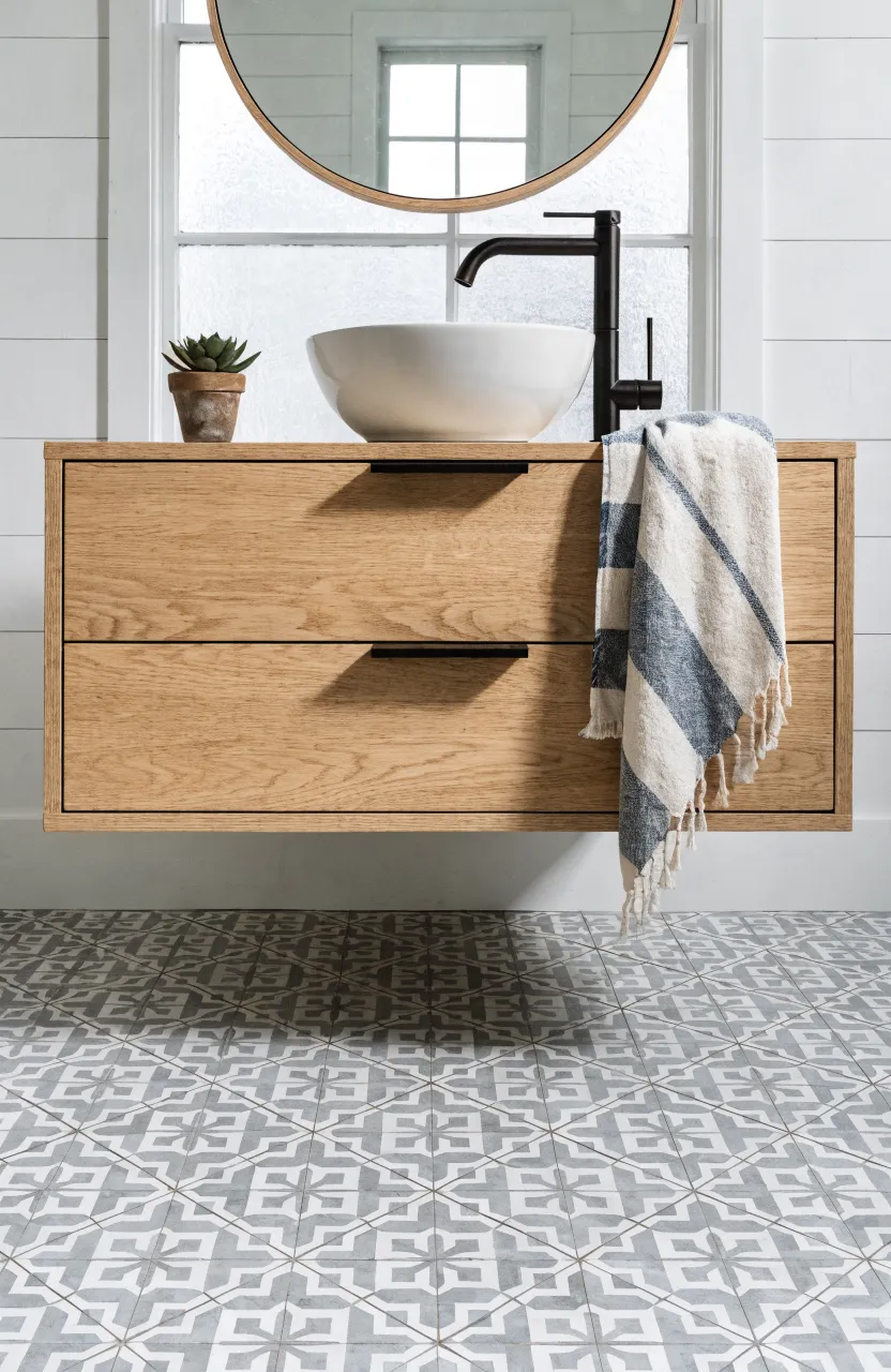 A floating light oak vanity with matte black handles and a white vessel sink in a boho bathroom.