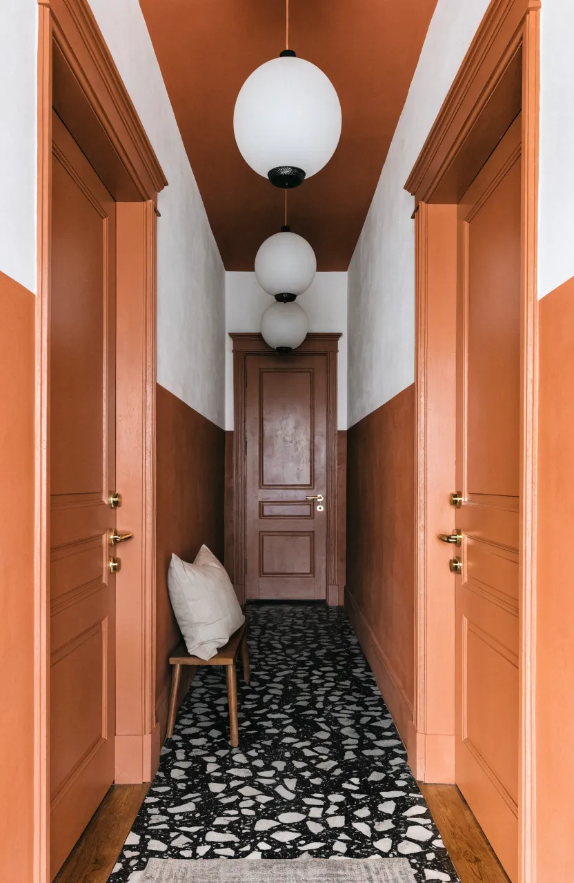 Symmetrical hallway with terracotta and white color-blocking and spotted terrazzo floors.