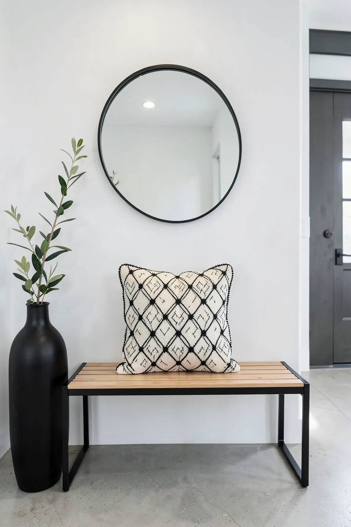 A tufted geometric pillow with black and cream patterns on a modern entryway bench.
