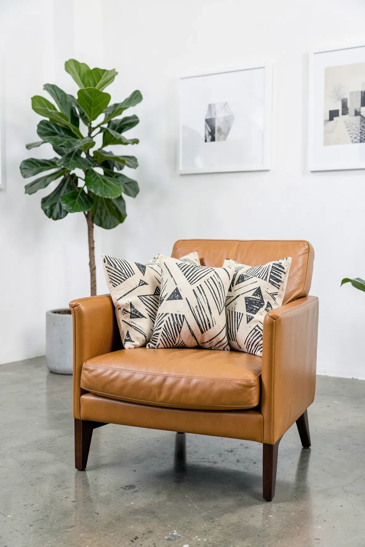 Beige canvas pillows with black stenciled geometric designs on a cognac leather chair.