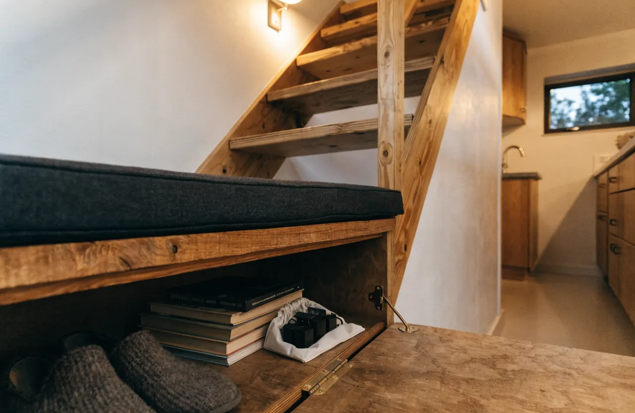 Tiny house loft stair landing used as a small seat with hidden storage below