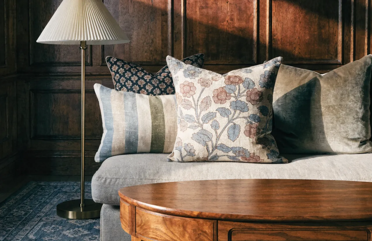 Patterned pillows mixing large floral, small stripe, and block print scale on a sofa