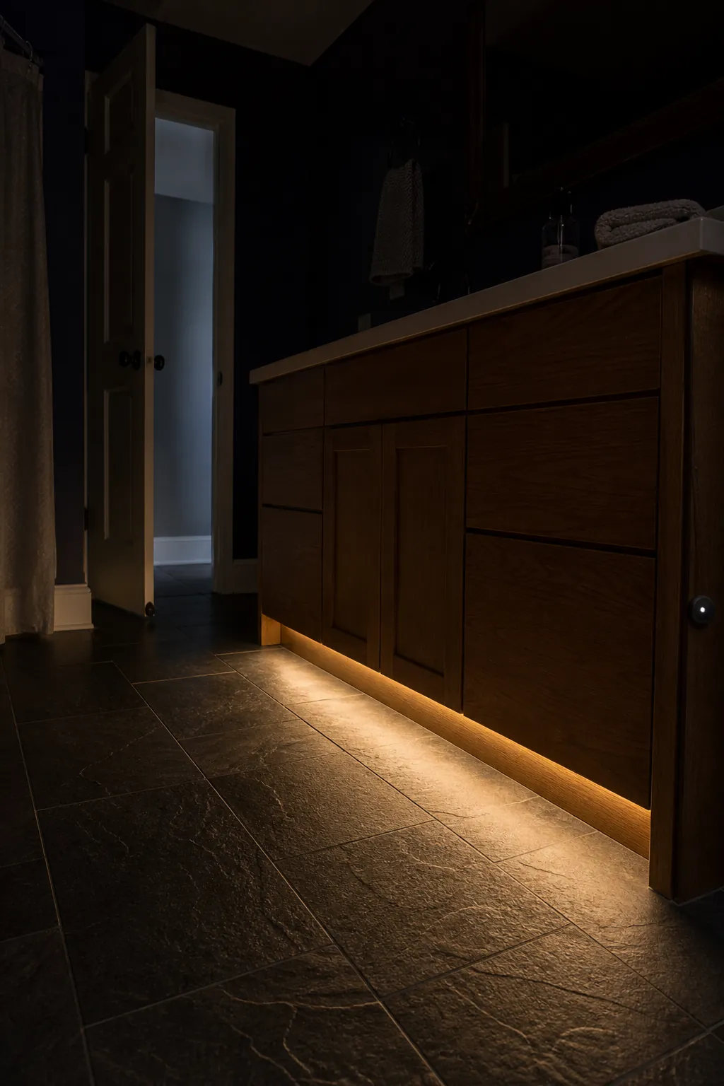 Hidden toe-kick lighting beneath a bathroom vanity at night