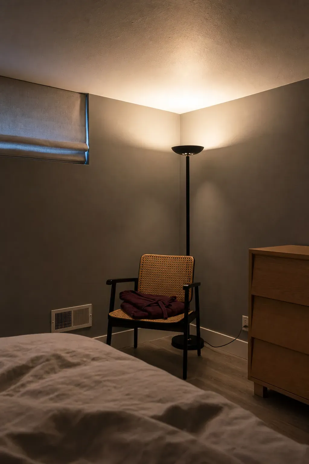 Slim floor uplight softening a dark small bedroom corner