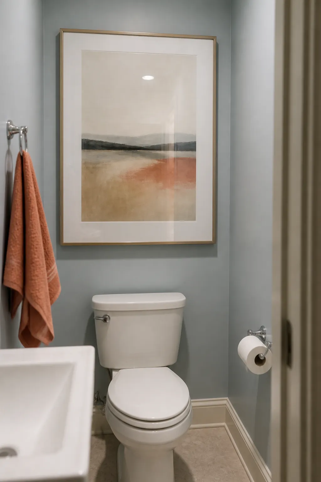 Half bath with one large framed artwork above the toilet instead of cluttered shelves