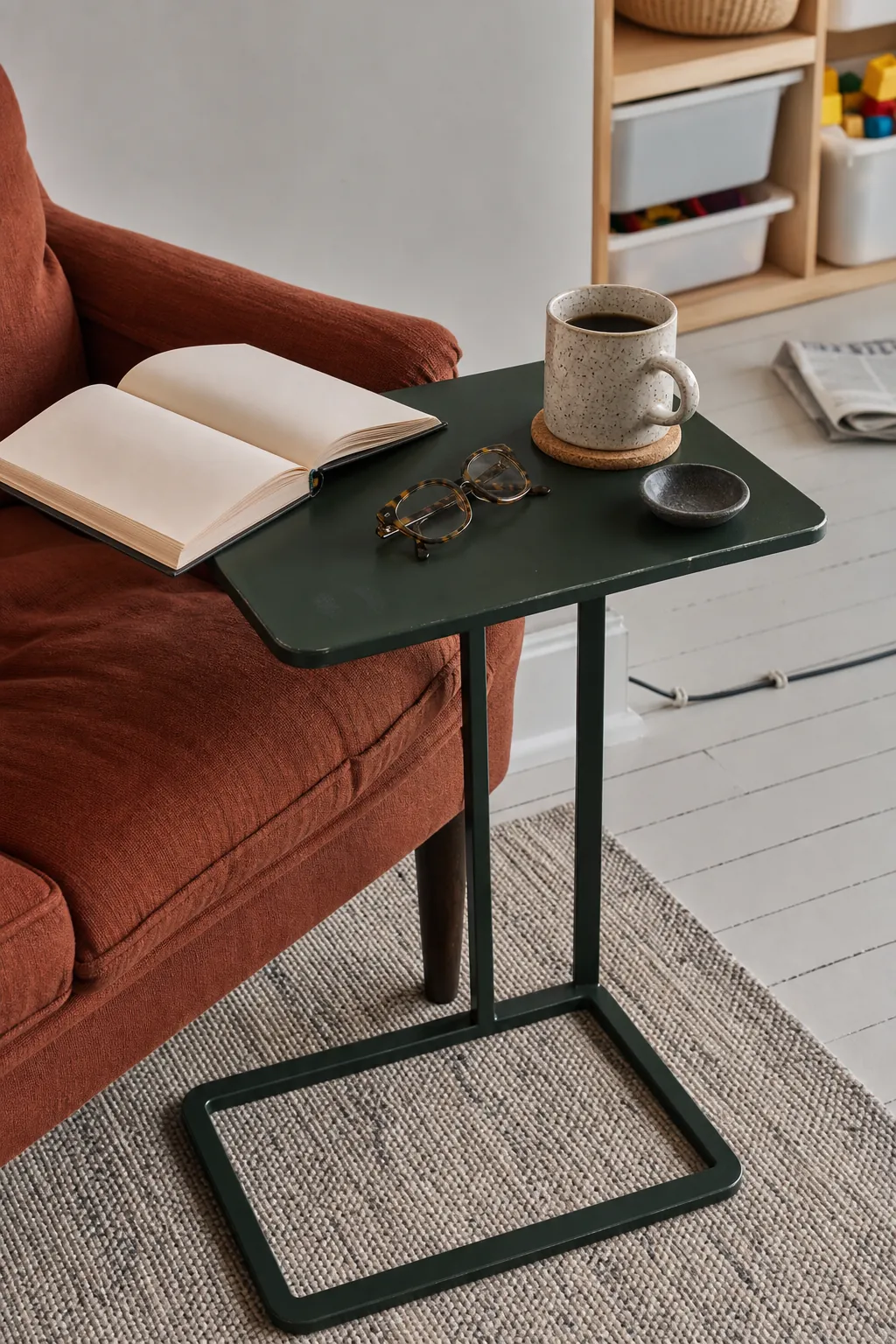 Small side table holding a book and mug next to a cozy reading chair