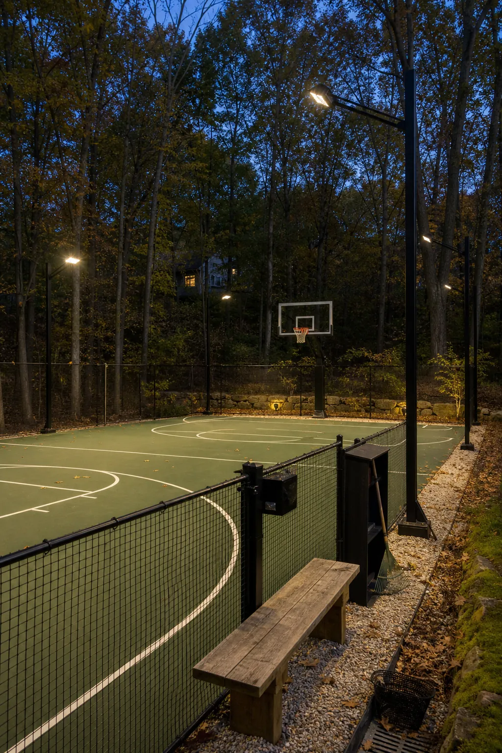 Woodland home basketball court with shielded low-glare evening lighting