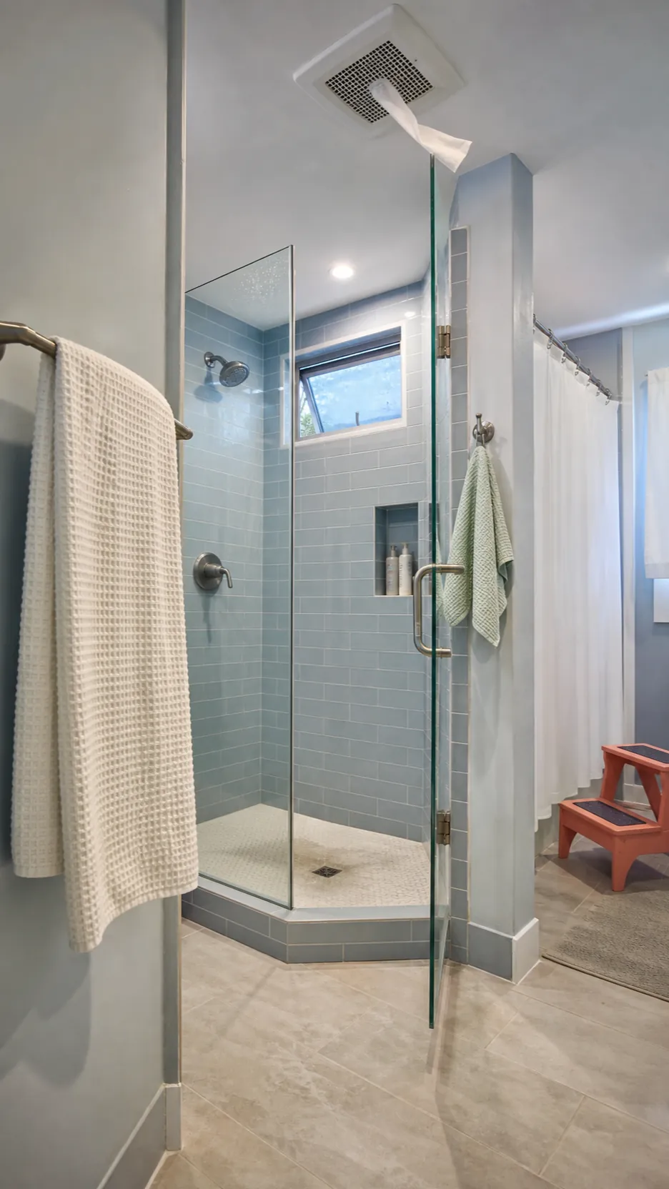Dry shower corner with running exhaust fan and freshly wiped silicone seams