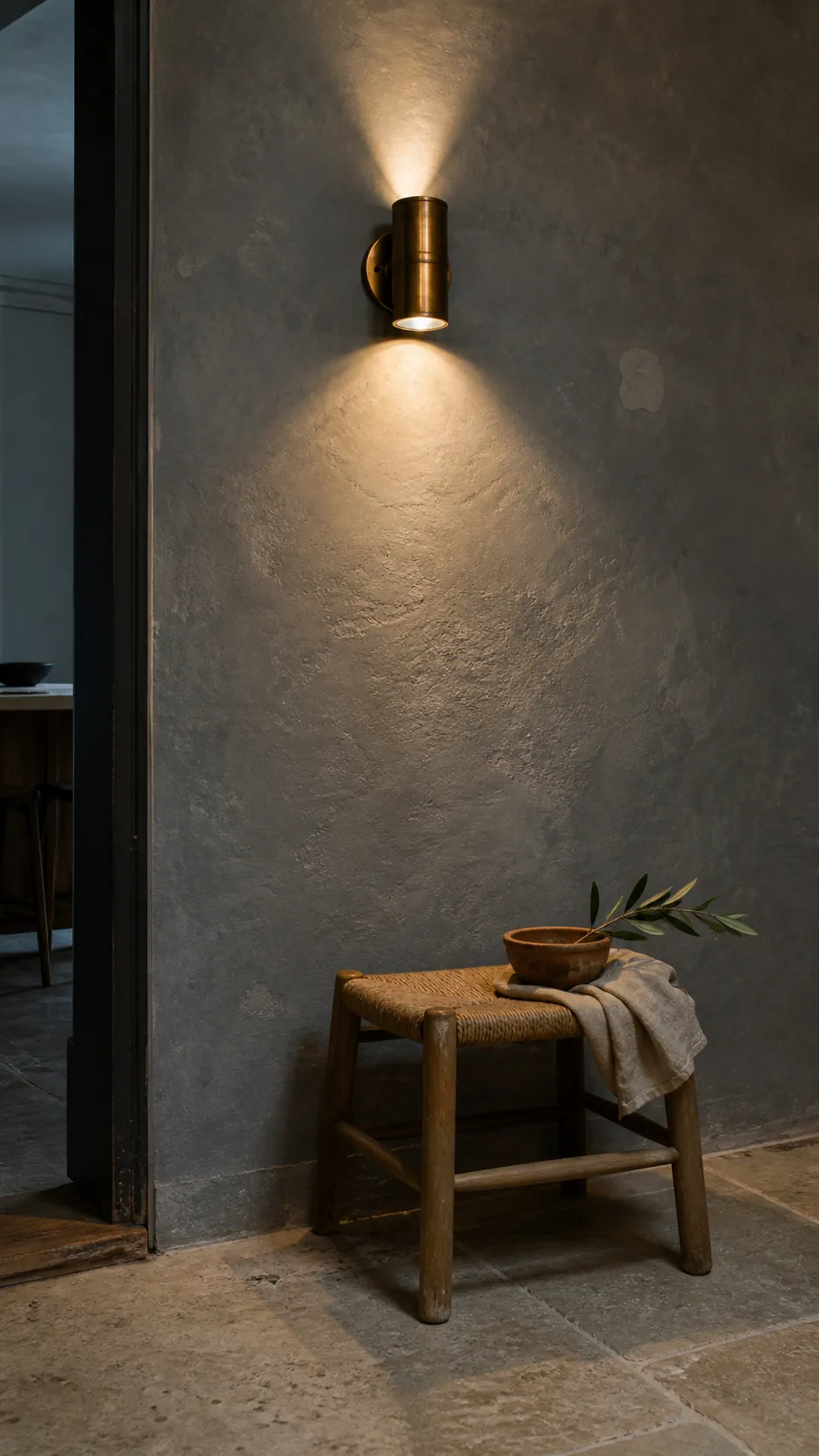 Antique brass up and down sconce illuminating a textured limewash wall