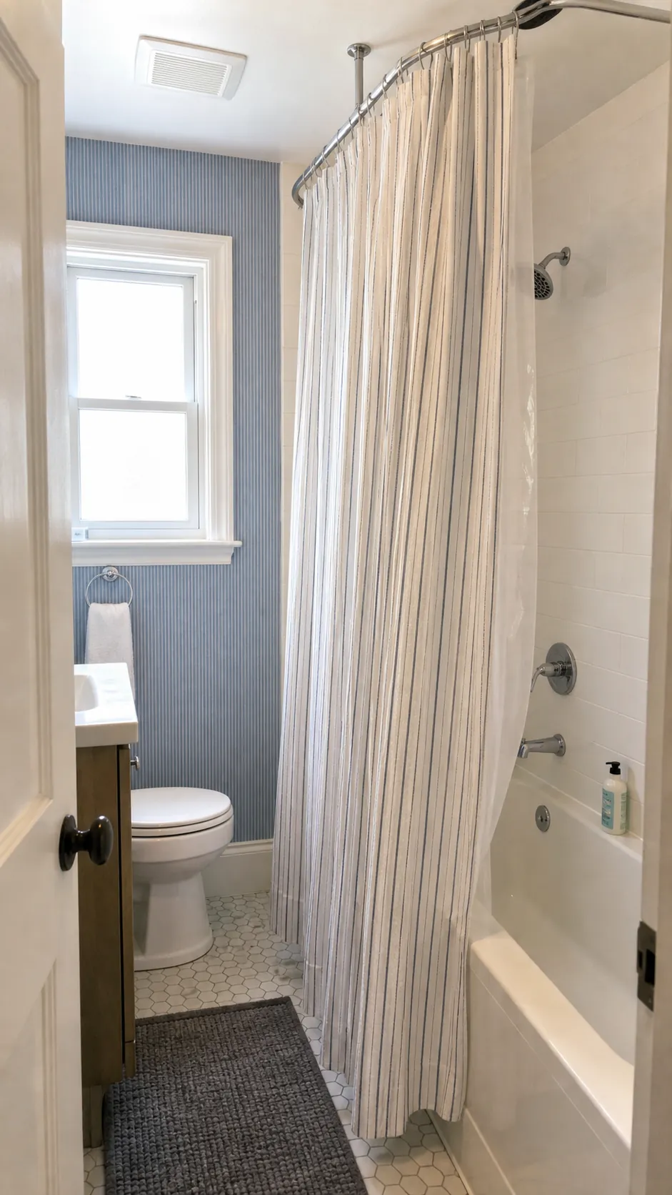Ceiling-mounted shower curtain making a small bathtub feel taller