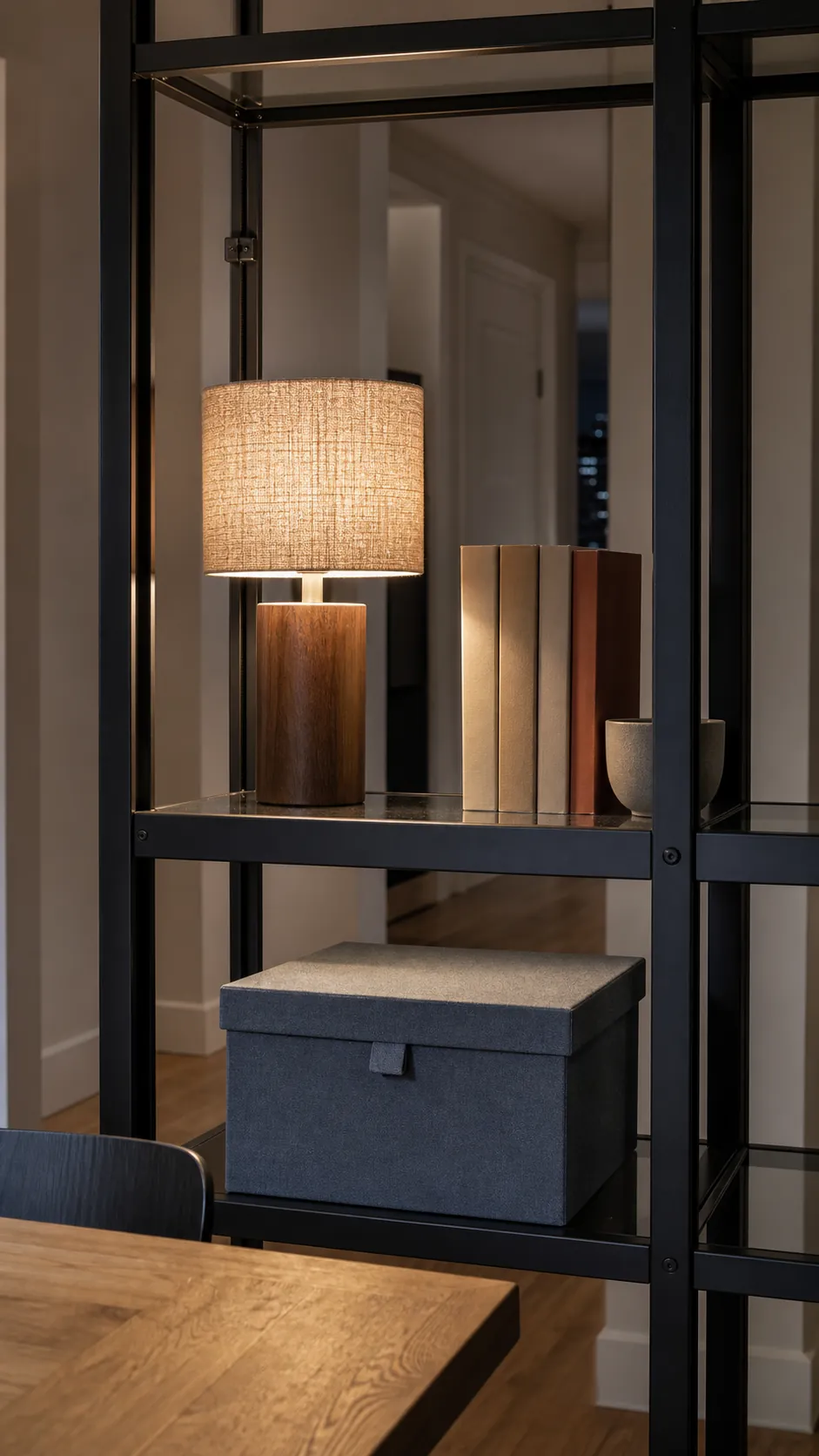 Linen shade lamp warming a black metal shelving unit