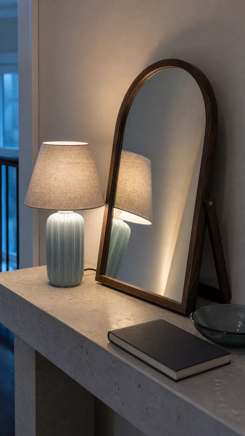 Small lamp reflected softly in an angled tabletop mirror