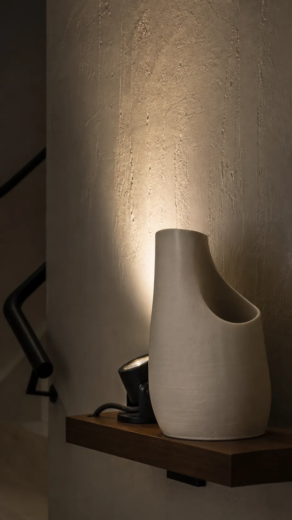 Hidden puck-style lamp casting light behind a sculptural object
