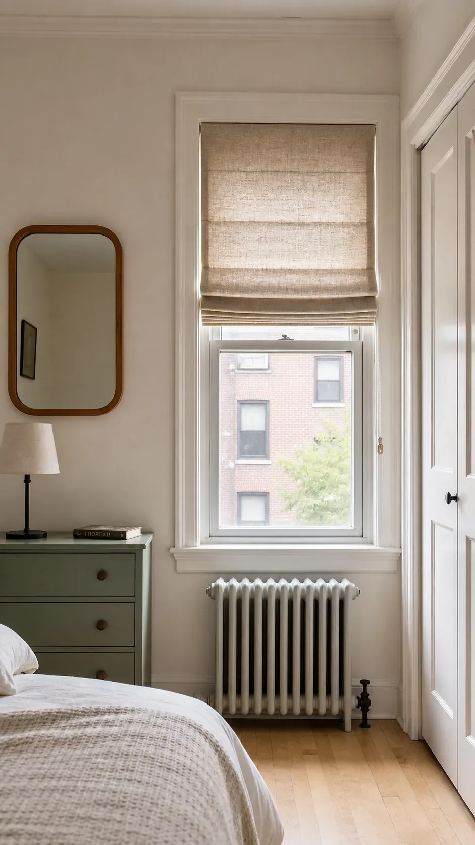 Off center bedroom window treated with a fitted Roman shade