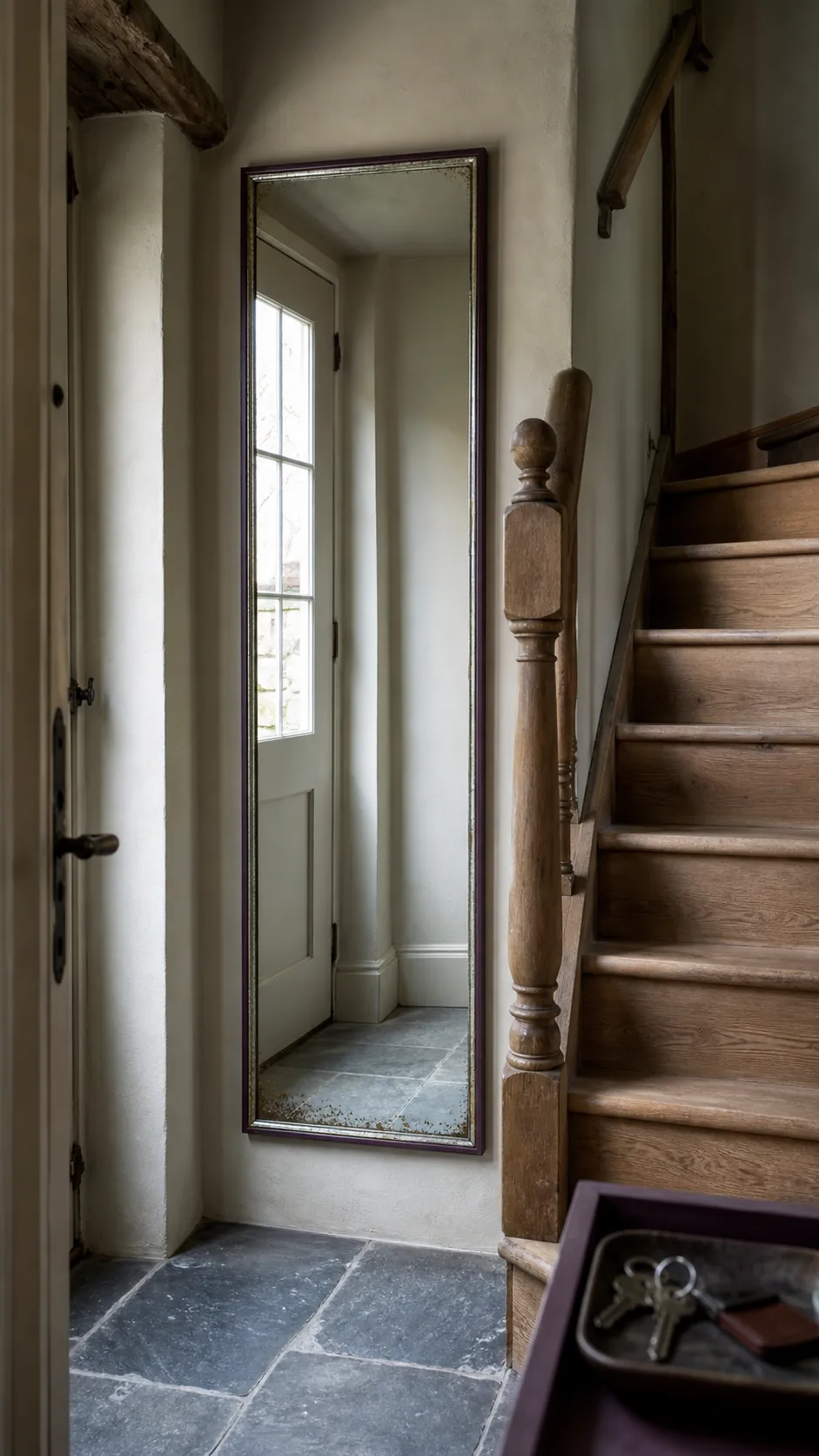 Entry mirror reflecting front-door light near a staircase