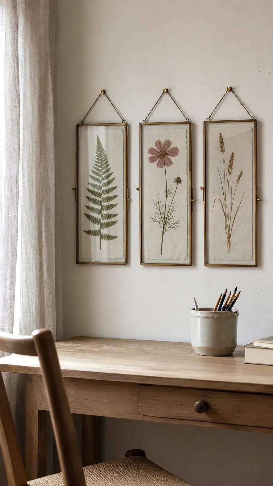 Pressed garden botanicals in simple glass frames above a bedroom desk