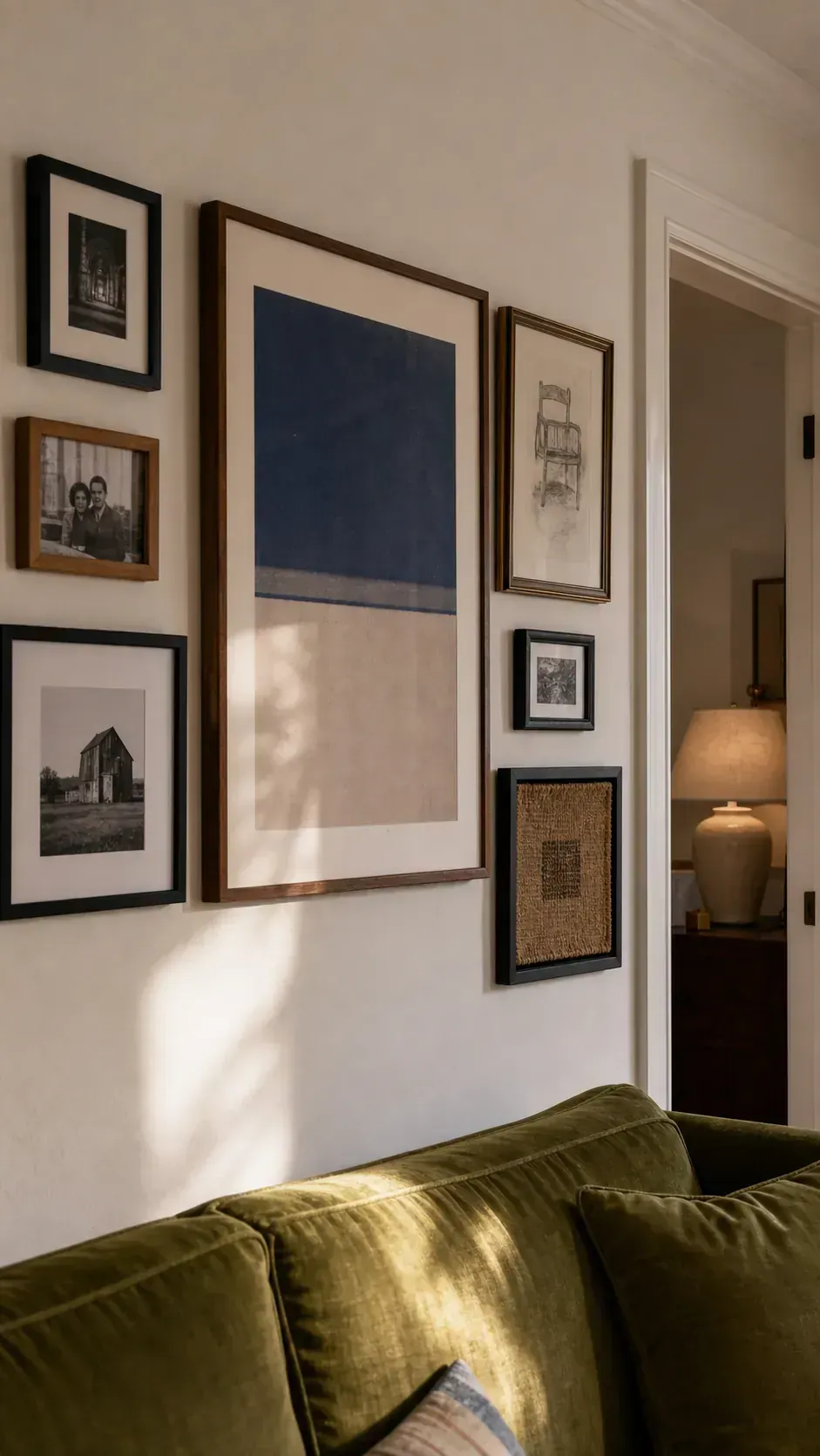 Eclectic gallery wall unified by black, walnut, and aged brass frames