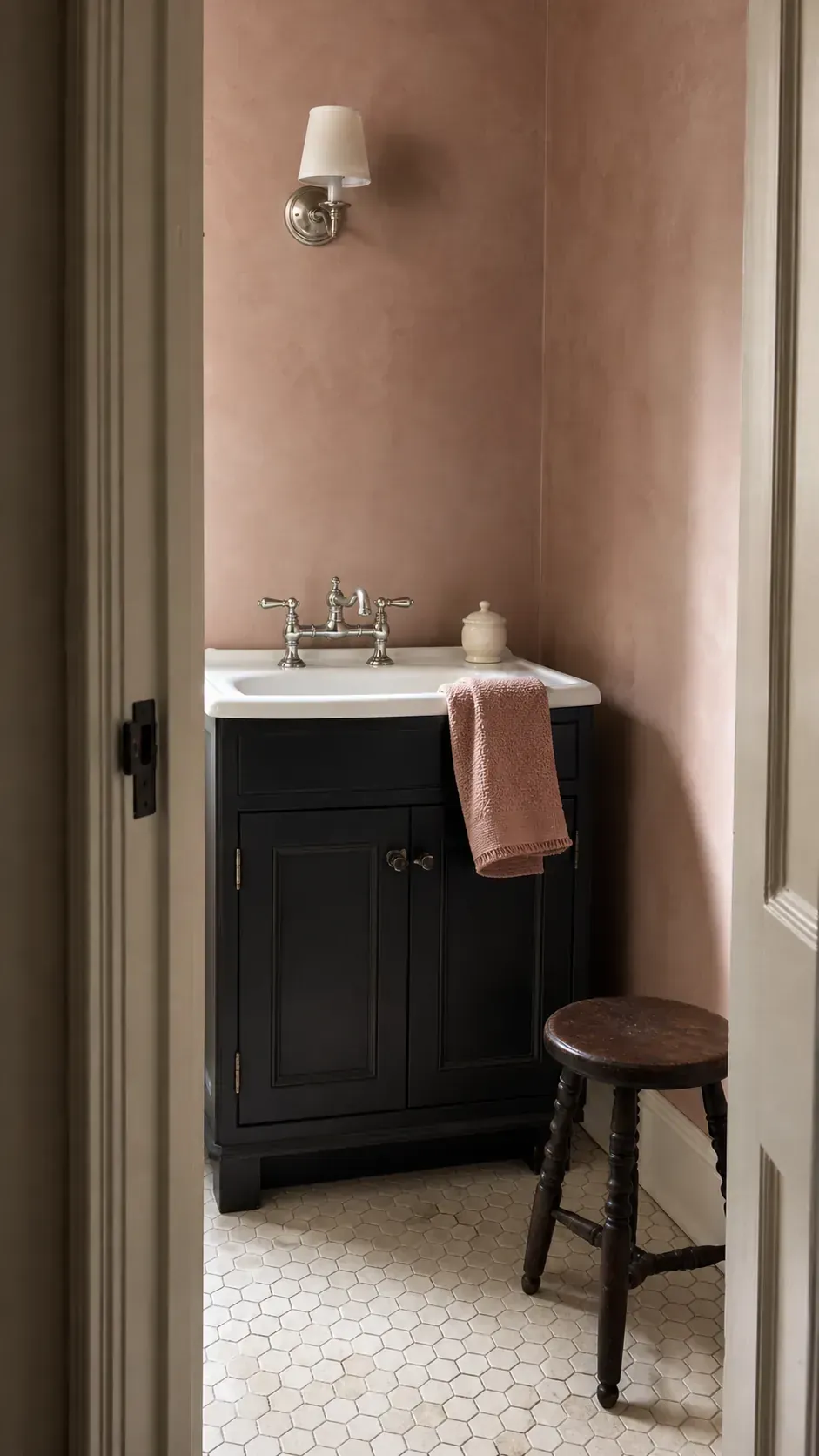 Black bathroom vanity styled against muted blush clay walls