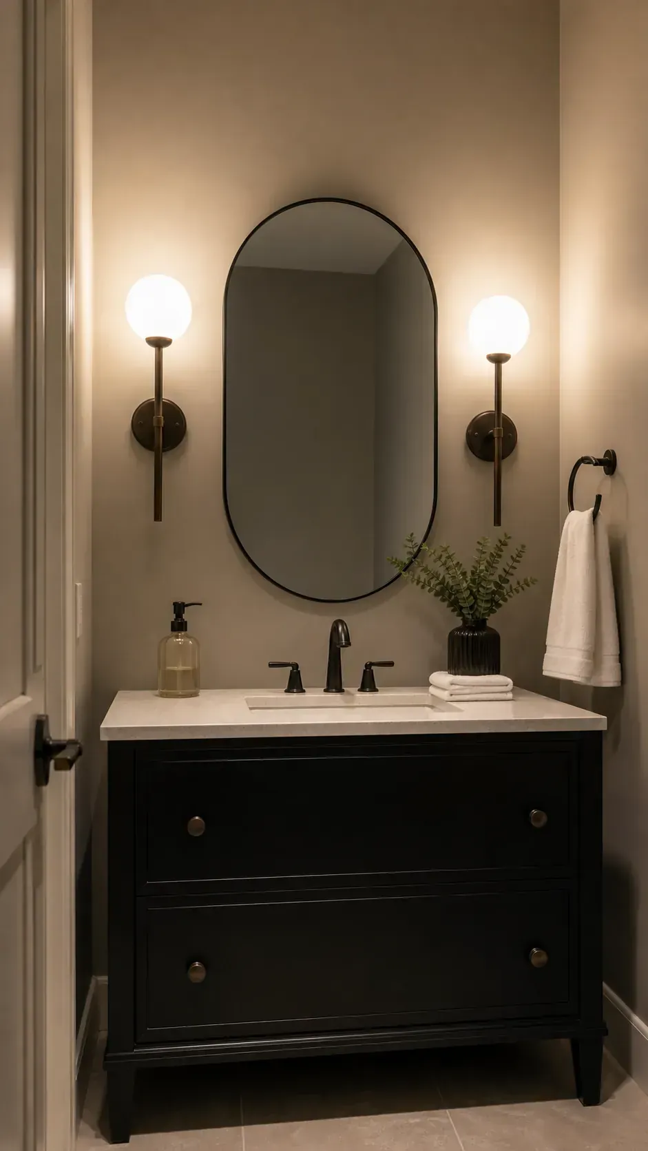 Black bathroom vanity lit by warm frosted globe sconces