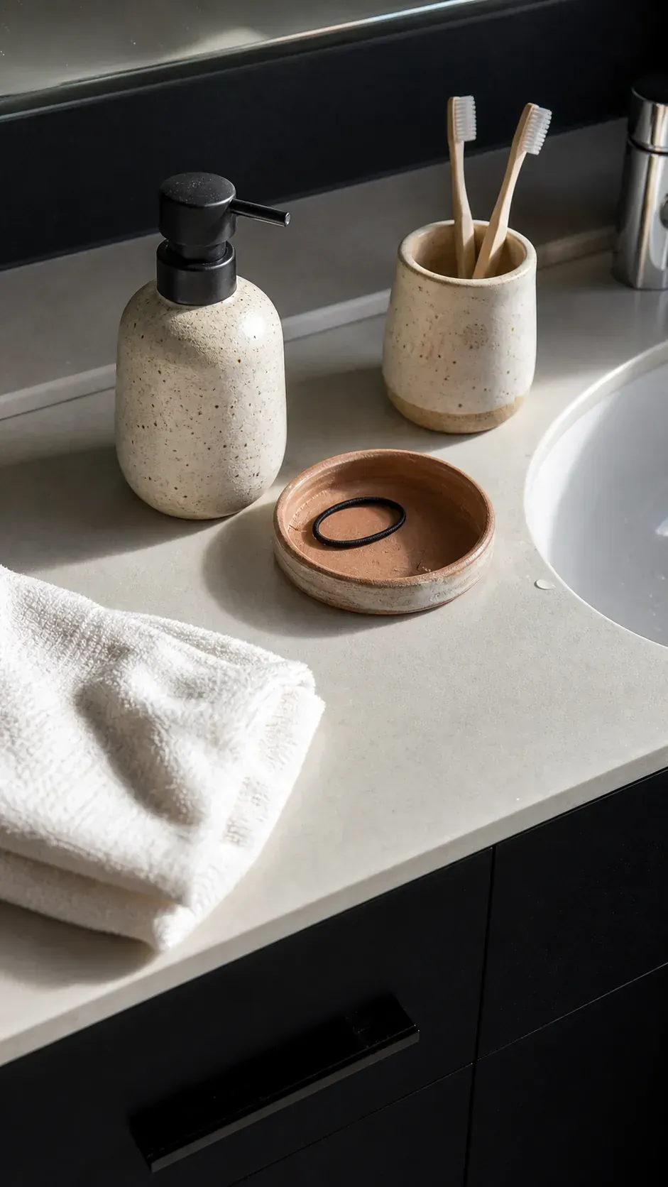 Black bathroom vanity styled with handmade ceramic accessories
